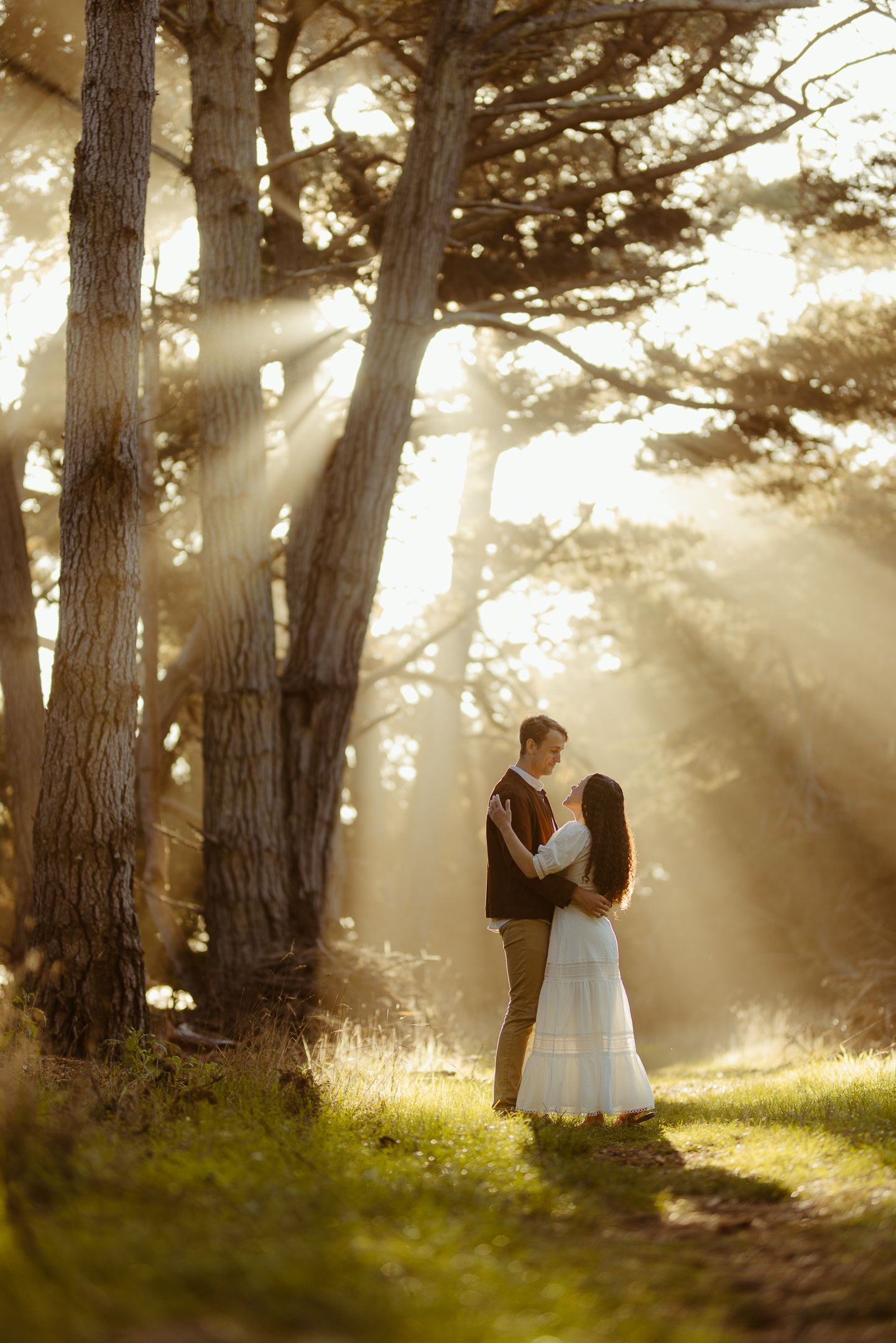 Couple dancing in a misty forest clearing as sunbeams stream through the trees, dreamy woodland elopement photography
