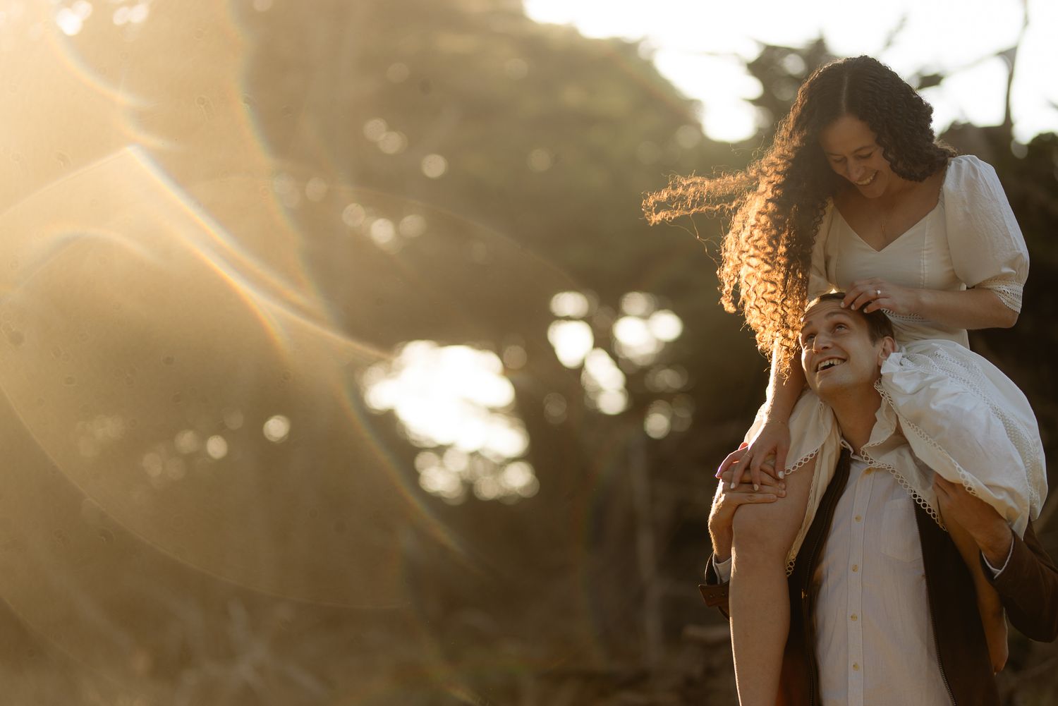 Couple embracing among sunlit pines as light streams through the trees, romantic forest elopement photography