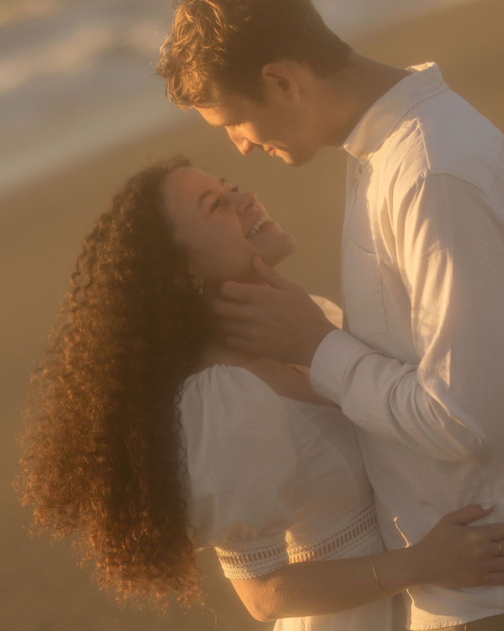 Couple sharing a tender moment nose to nose in glowing golden light, romantic coastal elopement photography