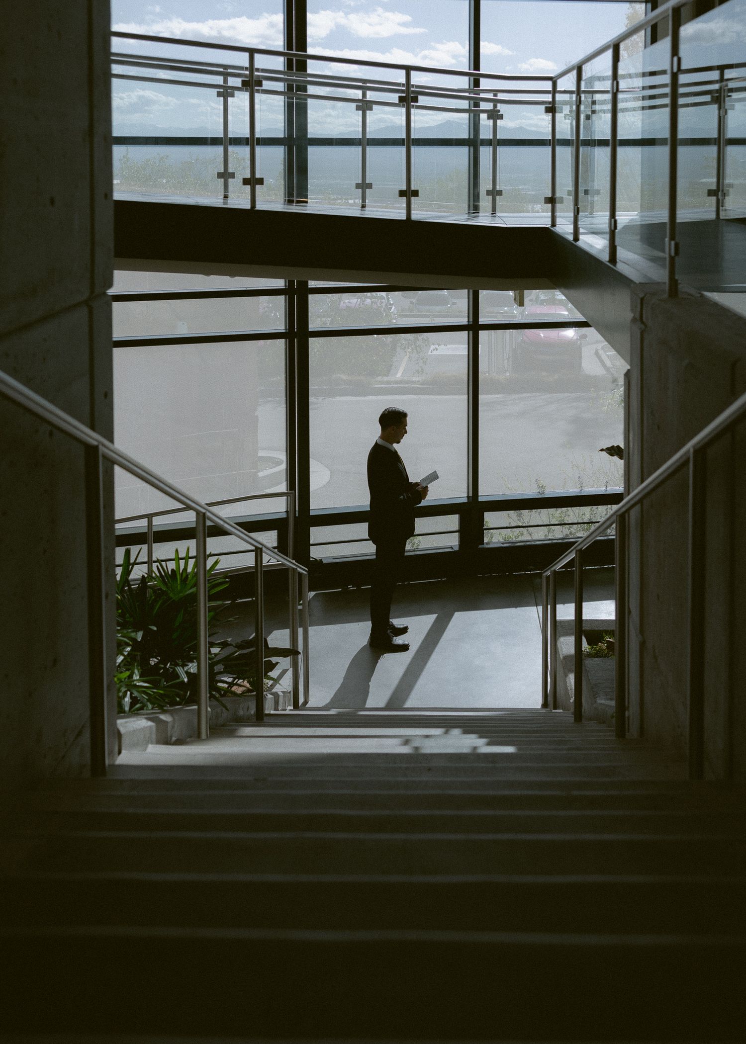 Cinematic architectural portrait of the groom during a first look in a glass-walled venue, by Sammy Aucella Photography