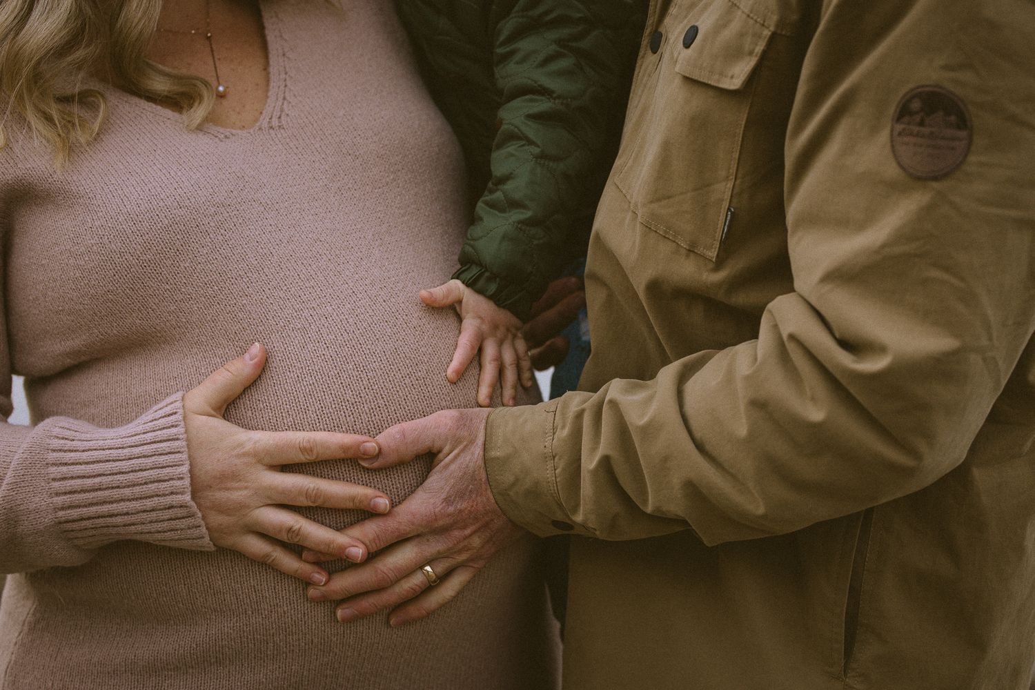 Close-up of an expectant mother's belly cradled by her own and her partner's hands, tender maternity session detail