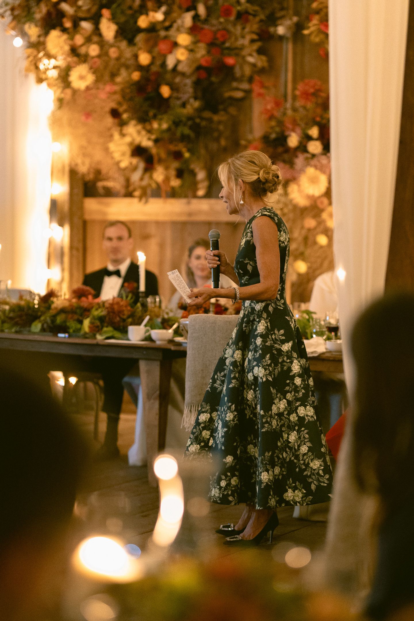 Guest in an emerald floral gown toasting amid florals at a Cuffey's Cove wedding in Elk, Mendocino, by Sammy Aucella Photography