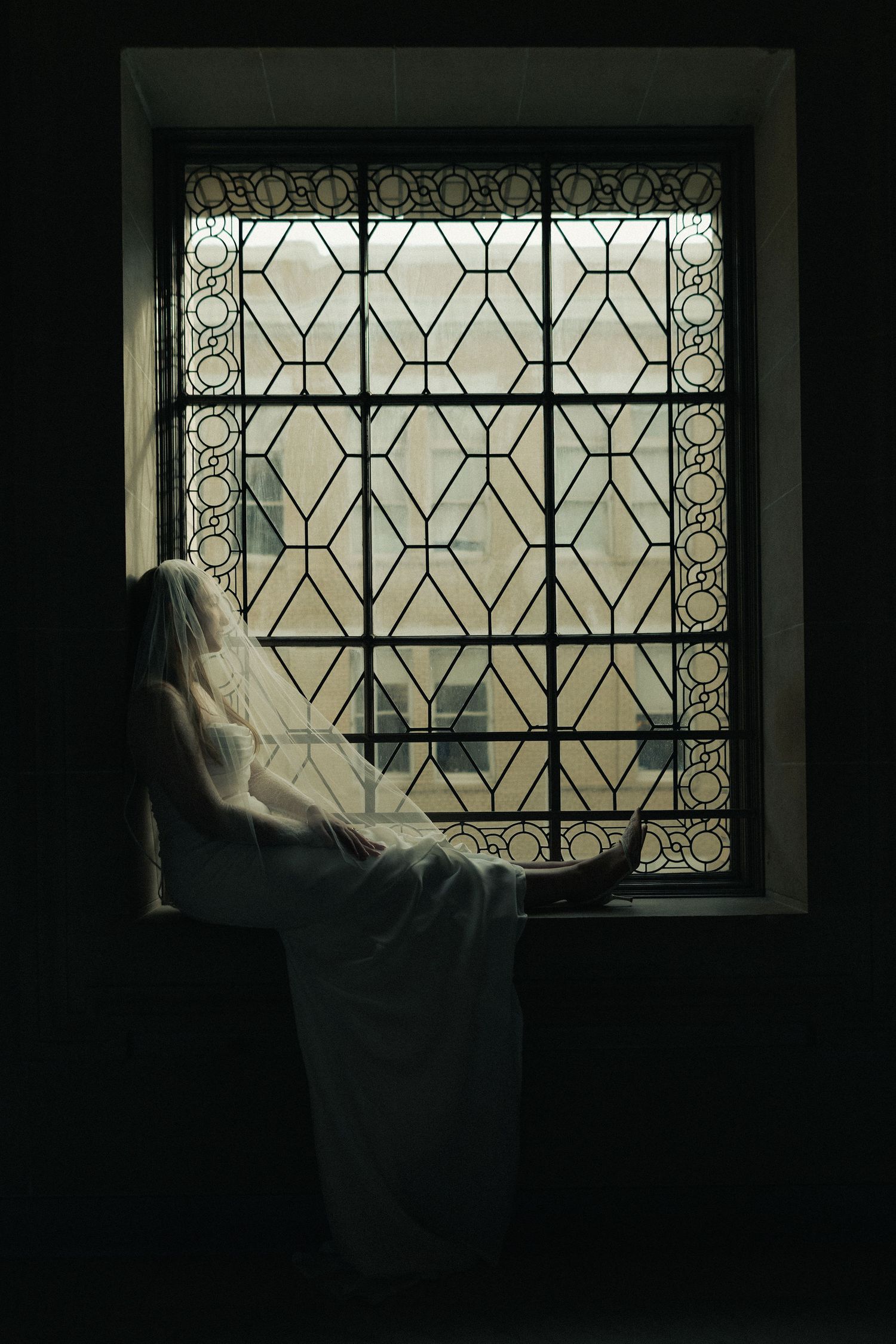 Bride beside an arched window at a San Francisco City Hall elopement, by Sammy Aucella Photography