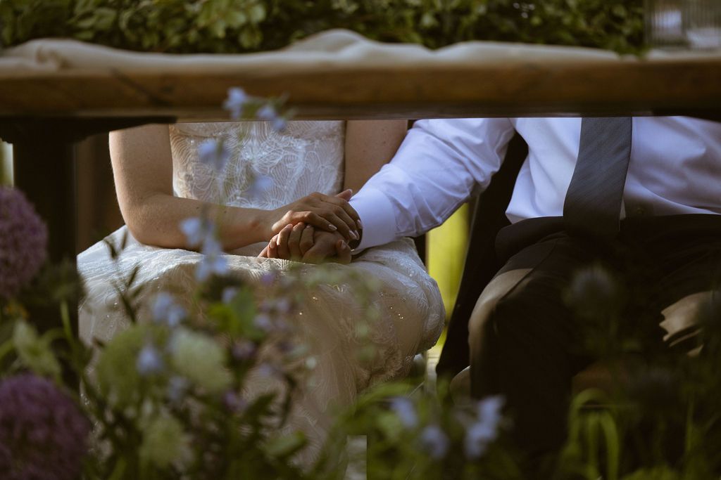 Couple holding hands across a floral table at a Nakoma Resort wedding in Clio, California, by Sammy Aucella Photography