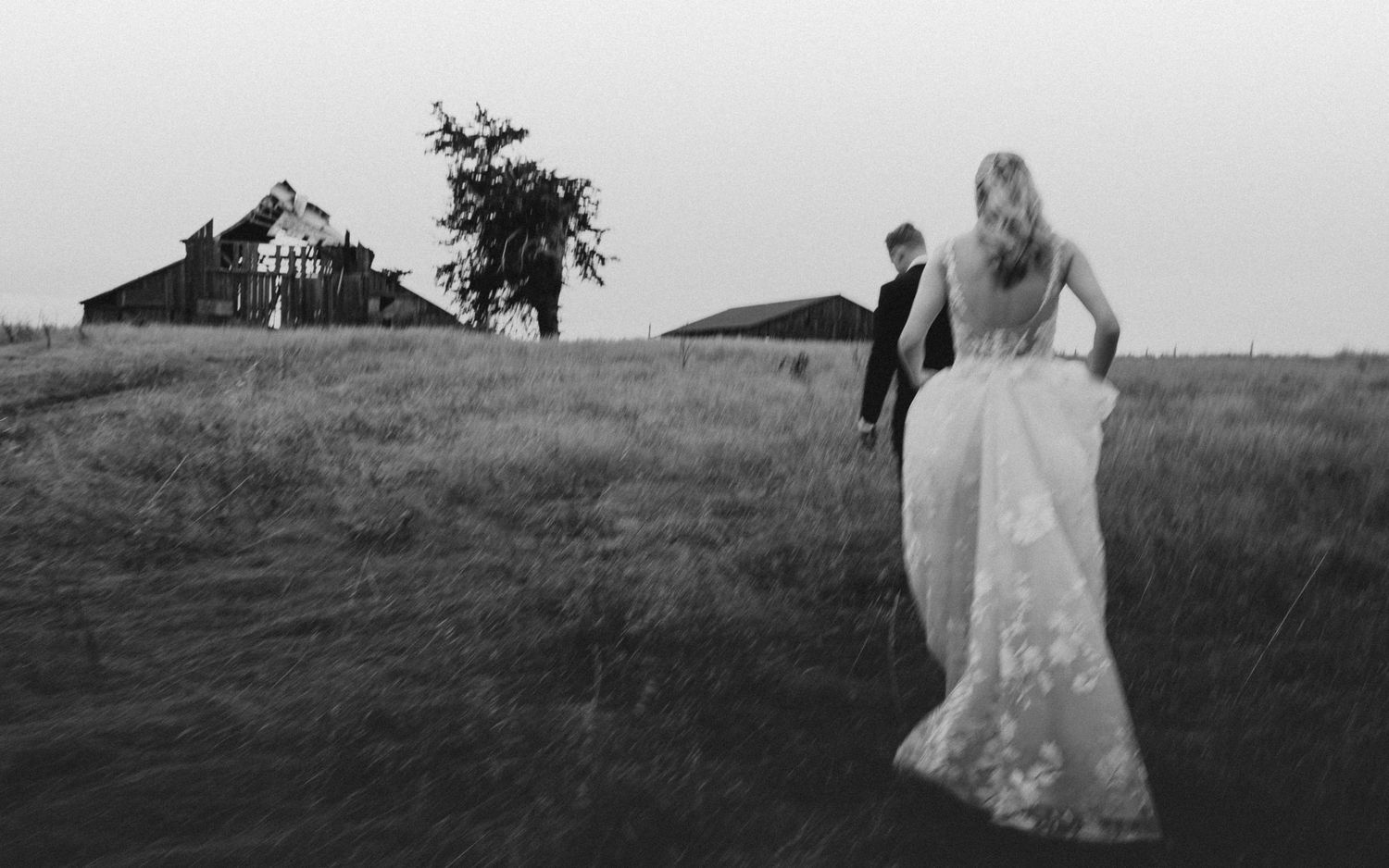 Story-driven black and white of the couple by the barn at a Switzer Farm Mendocino cliffs wedding, by Sammy Aucella Photography