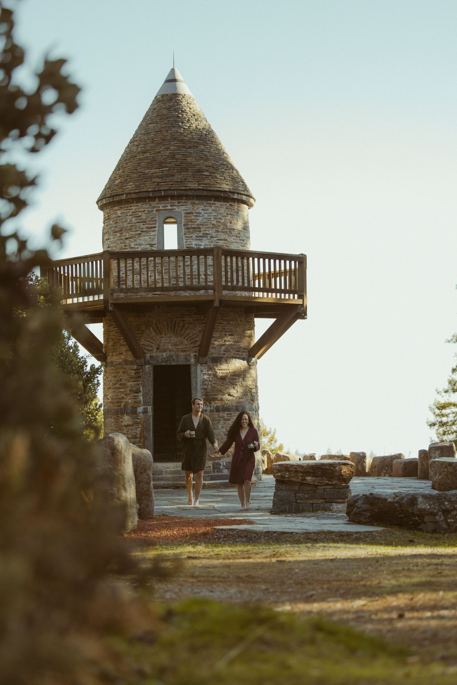 Couple standing at the base of a stone tower in a golden autumn mountain landscape, adventurous engagement session