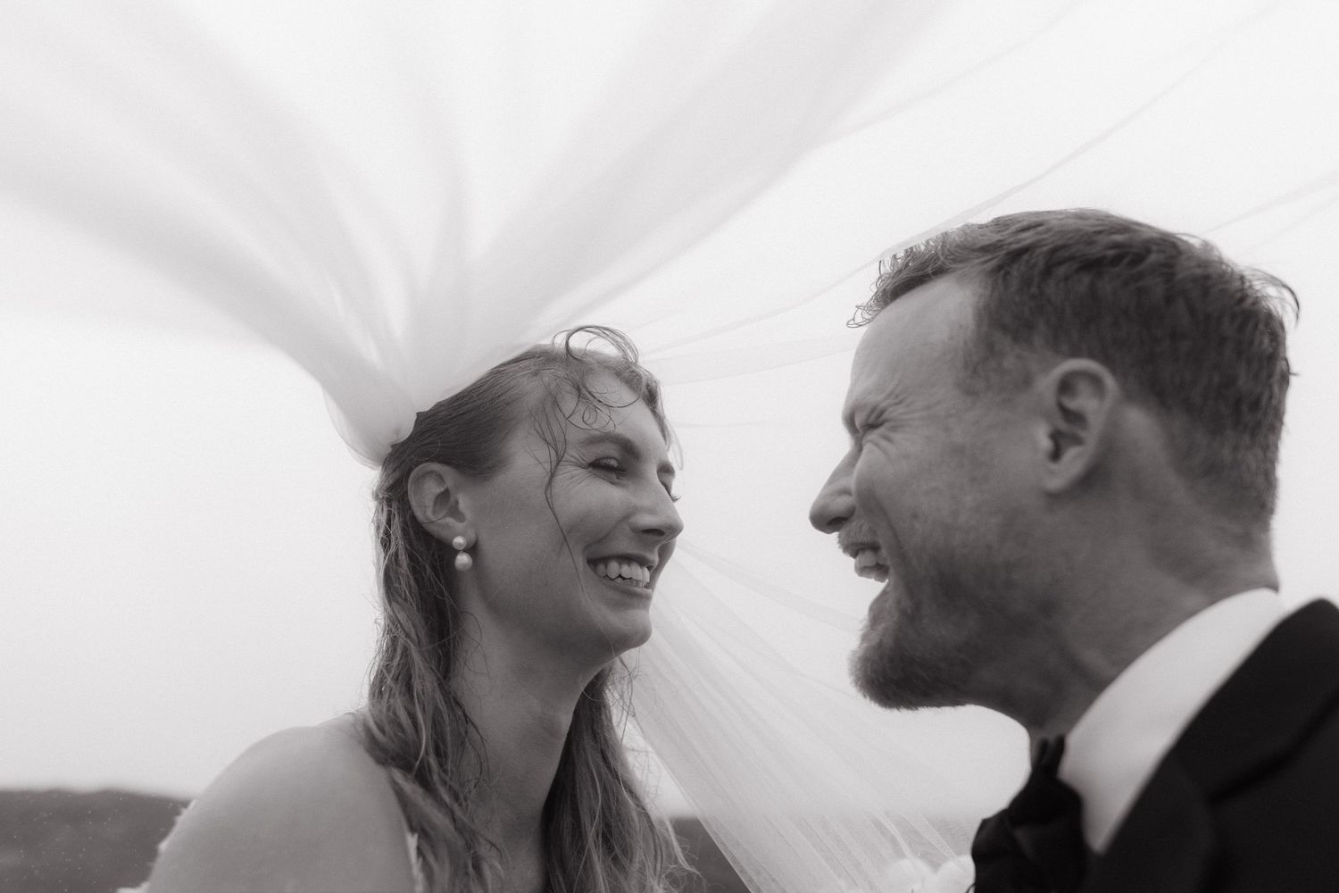 Black and white of the couple laughing beneath the veil at a Switzer Farm Mendocino cliffs wedding, by Sammy Aucella Photography