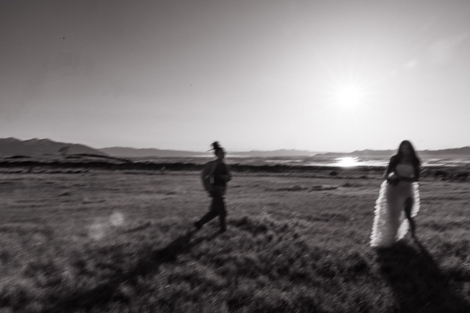 Black and white figure walking the salt flats into the sun, by Sammy Aucella Photography