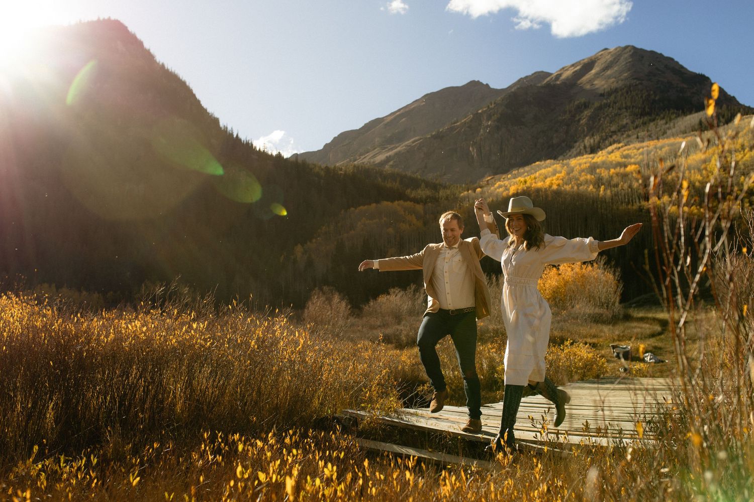 Couple dancing joyfully in fall Aspen Colorado foliage near Ashcroft Ghost Town during unique engagement session by Sammy Aucella Photograph