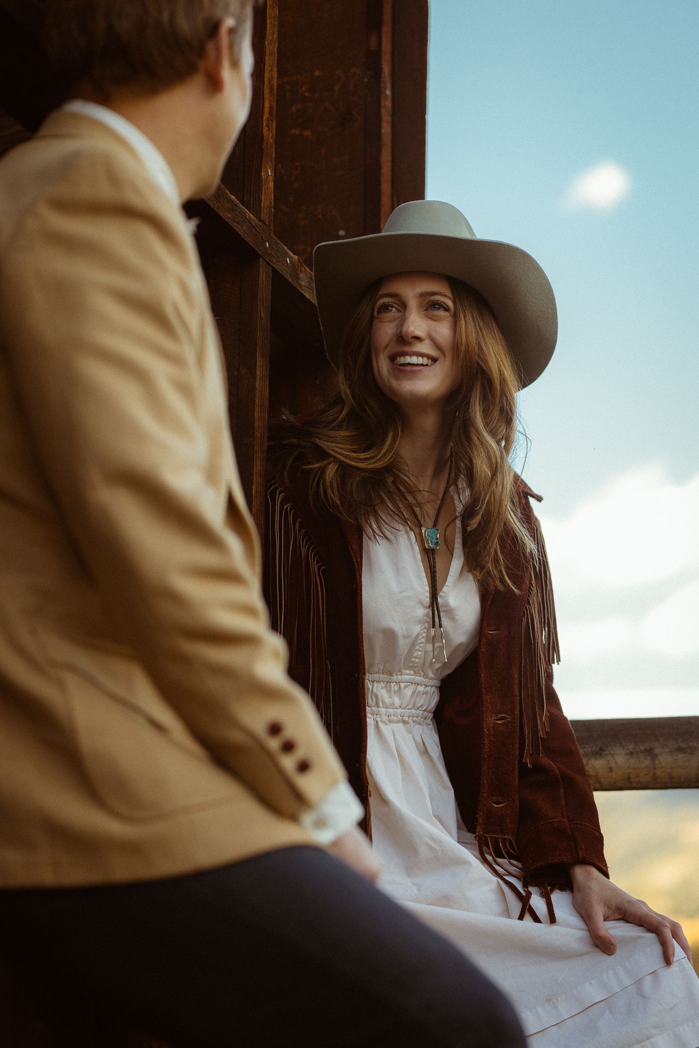 Couple in hats sharing a quiet moment in a sunlit field, romantic Western elopement photography
