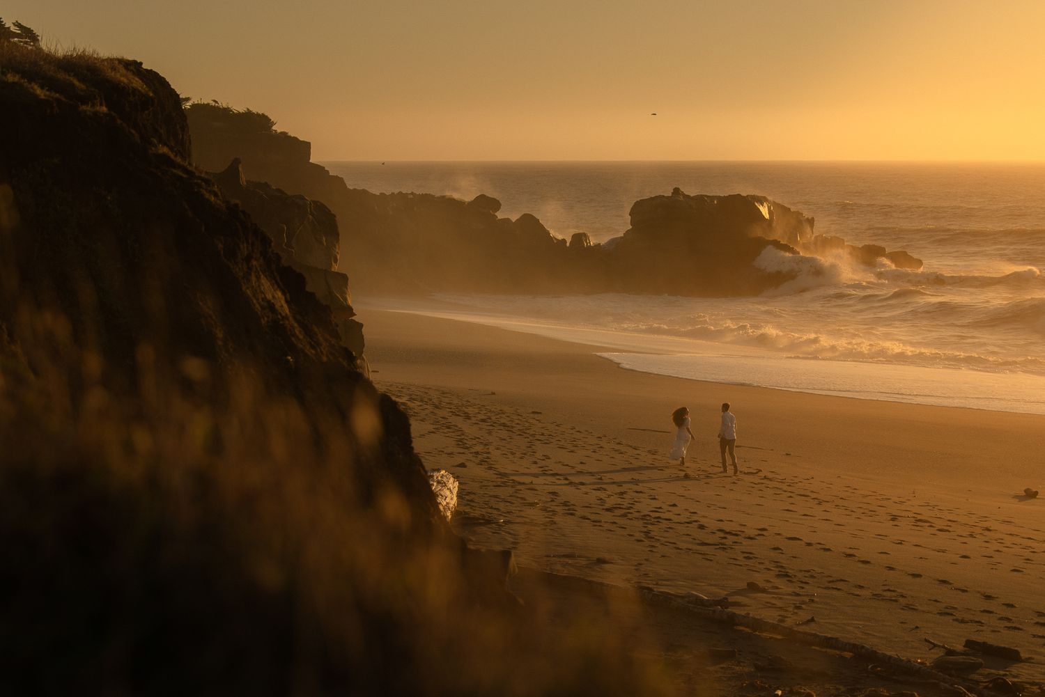 Golden light washing over a wide beach and coastal cliffs, sweeping travel landscape photography