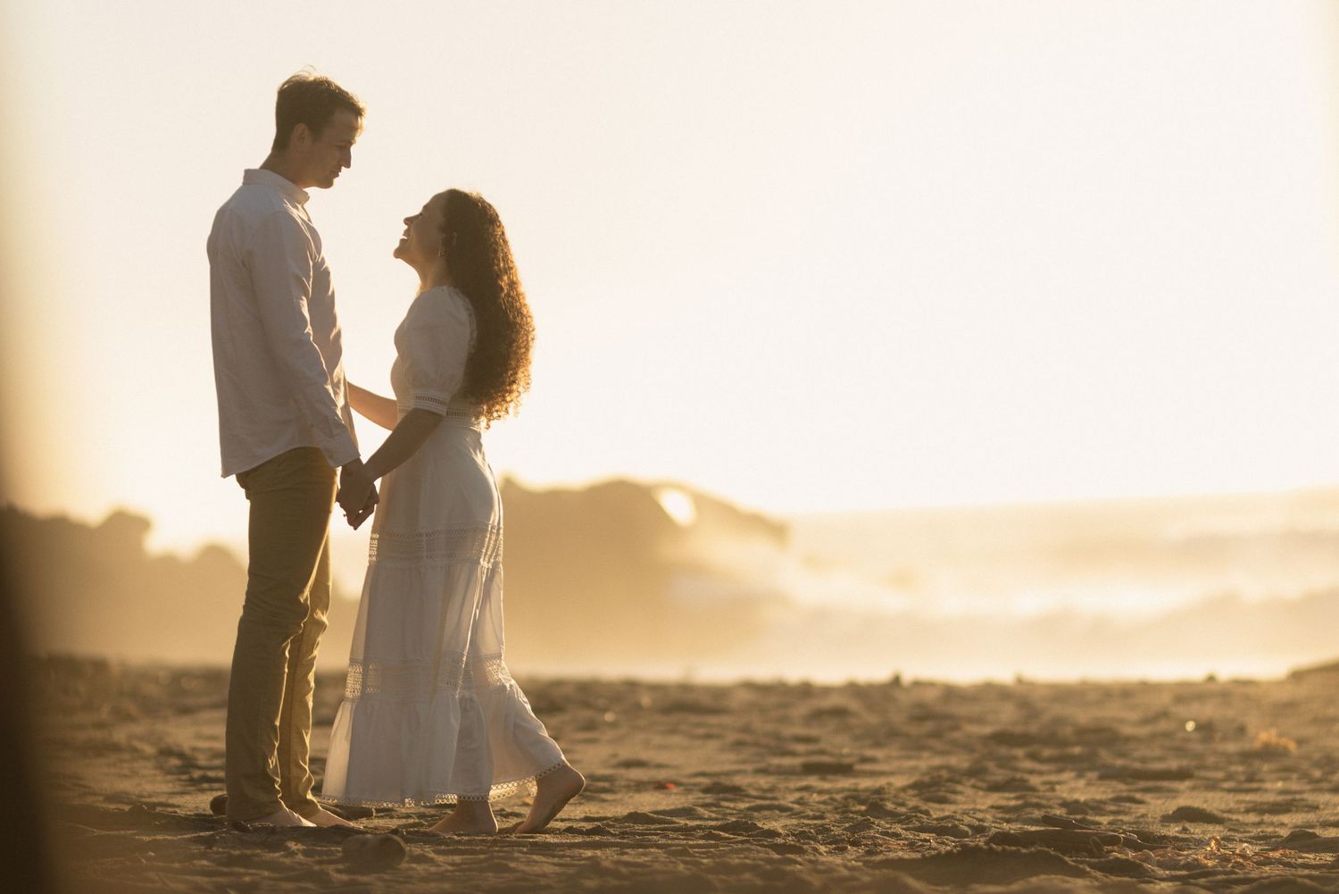 Couple standing close together on coastal cliffs at golden hour during romantic engagement session in Gualala California Mendocino CA by Sam