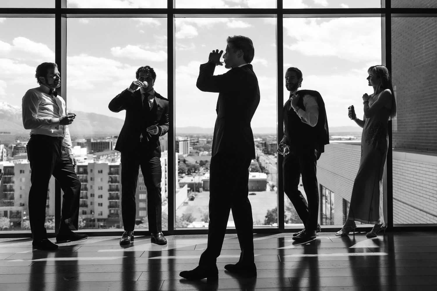 Editorial black and white of groomsmen by a city window at a New York luxury wedding, by Sammy Aucella Photography