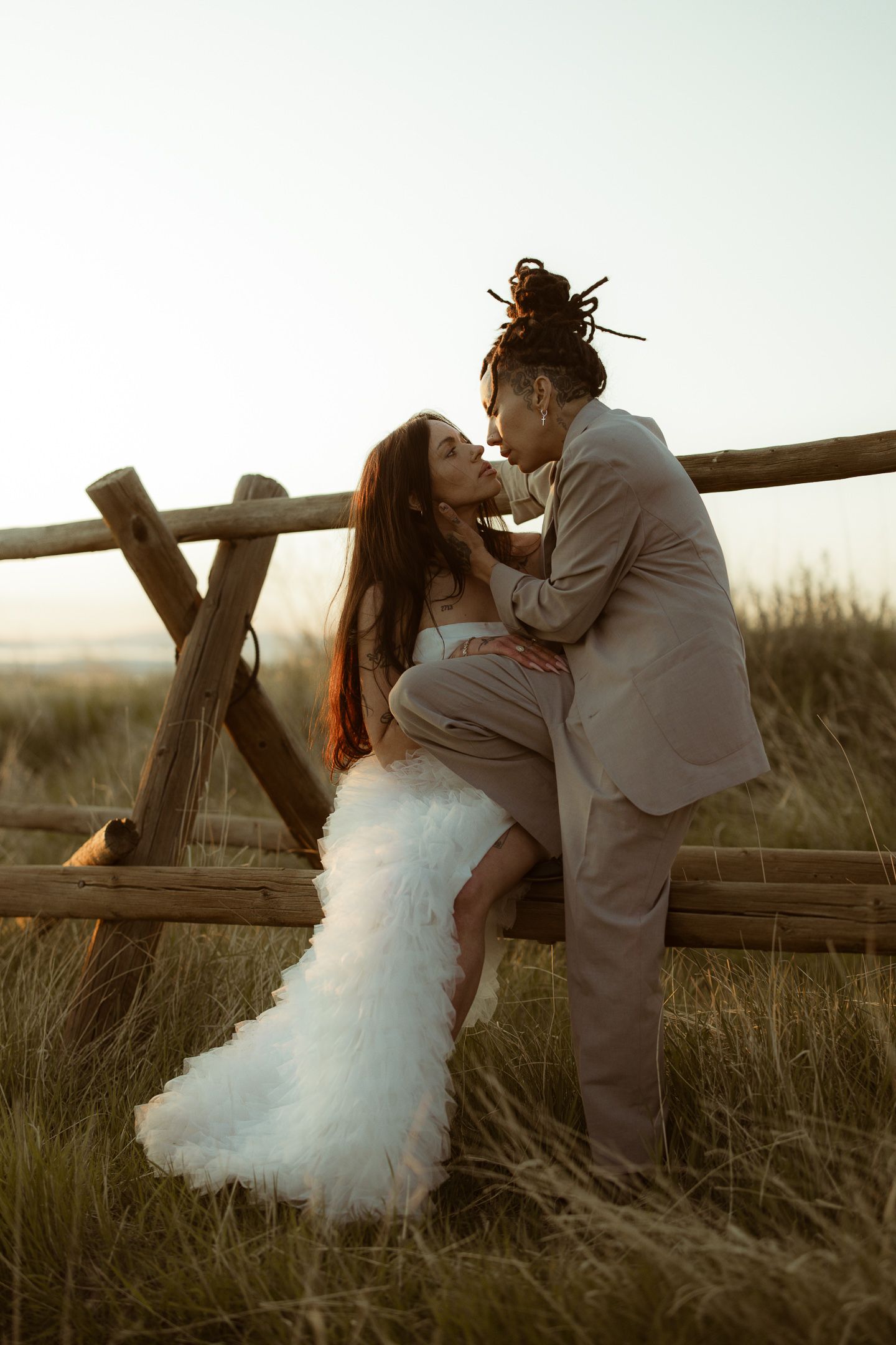 Couple kissing on a rustic wooden fence in a Utah field, by Sammy Aucella Photography