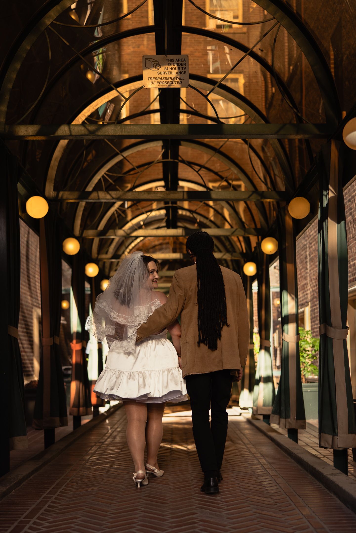 Couple beneath a string-lit walkway at an adventure session, by Sammy Aucella Photography