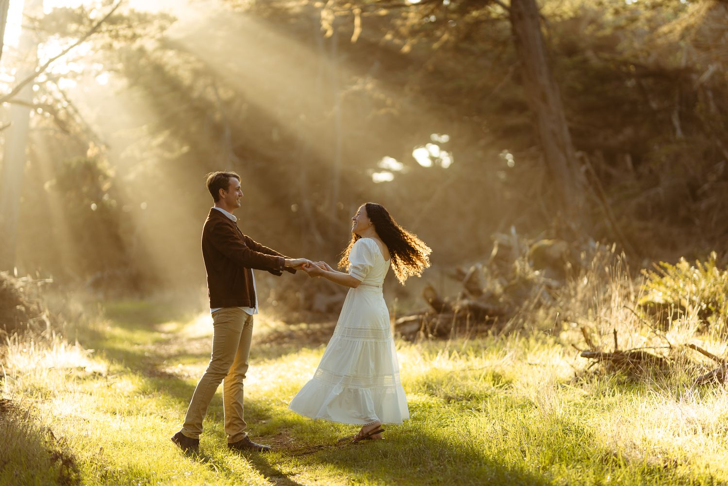 Couple dancing in a sunbeam-lit forest clearing, dreamy woodland elopement photography