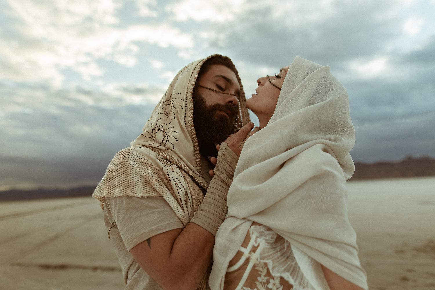 Couple in cream robes embracing in the Utah desert, by Sammy Aucella Photography