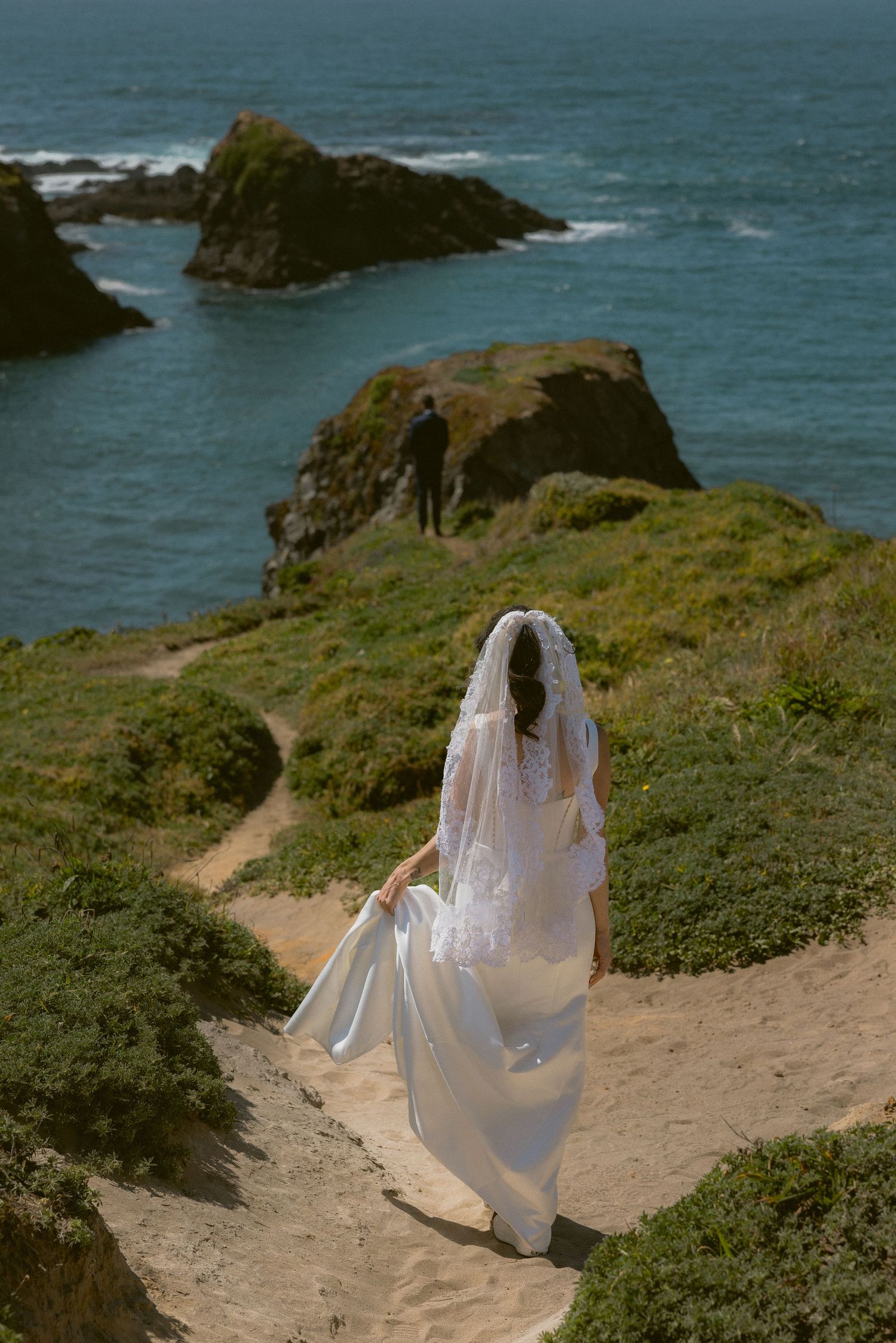 Bride with a long veil on the Mendocino cliffs during a coastal first look, by Sammy Aucella Photography