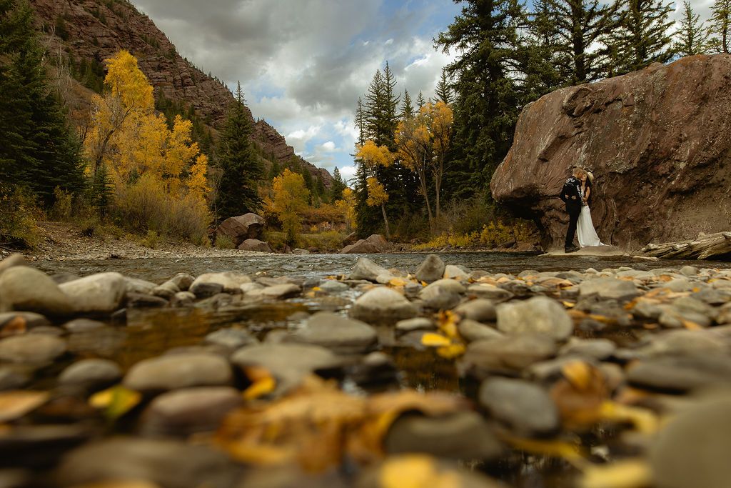 Couple by a mountain creek among golden autumn trees, by Sammy Aucella Photography