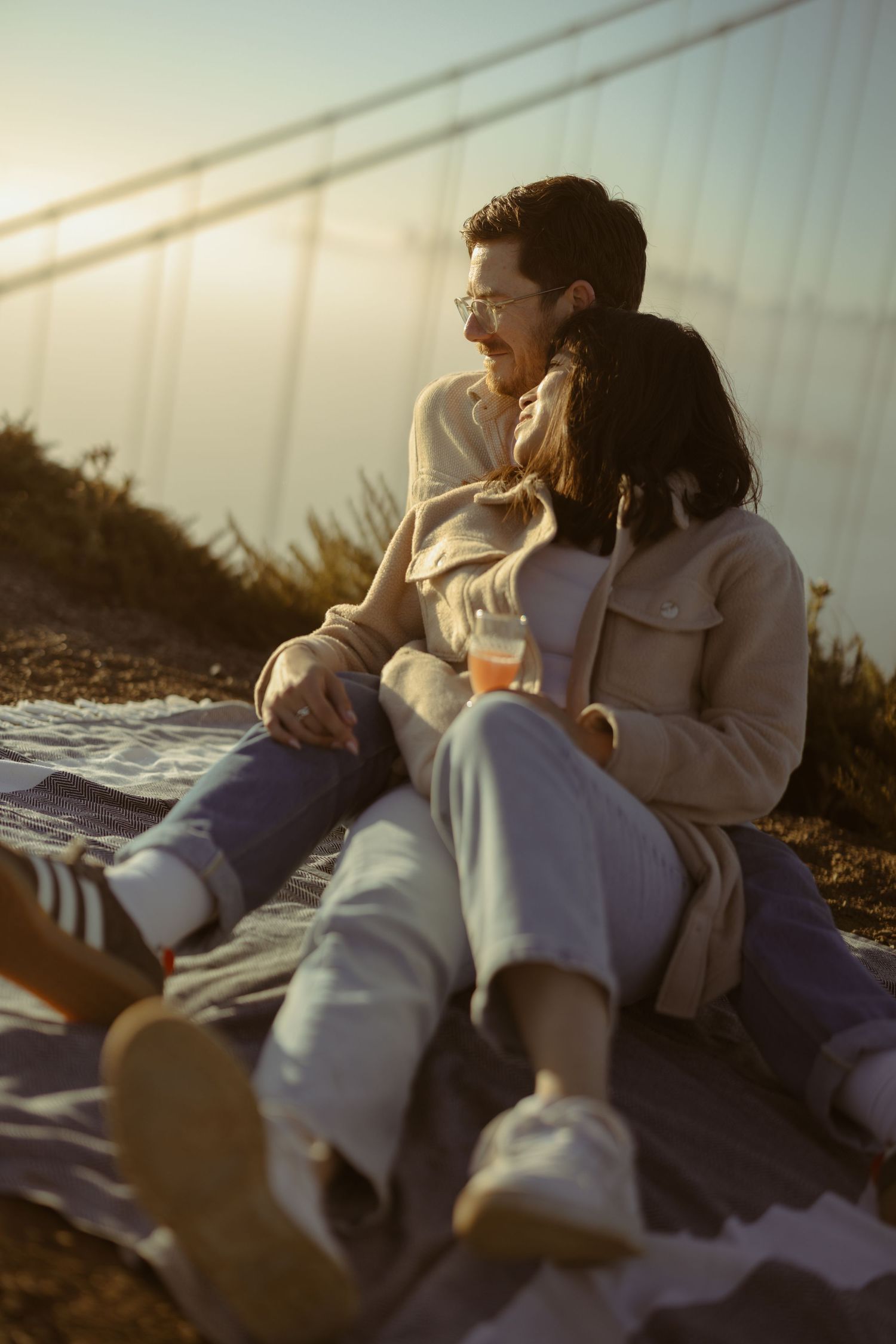 Couple sharing a cozy picnic on a blanket with the Golden Gate Bridge behind them, sweet San Francisco engagement session