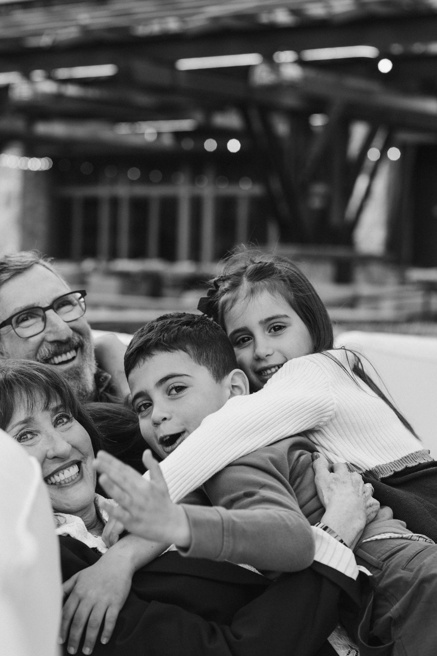 Black-and-white photo of a family wrapped in a joyful group hug, candid and emotional documentary family session