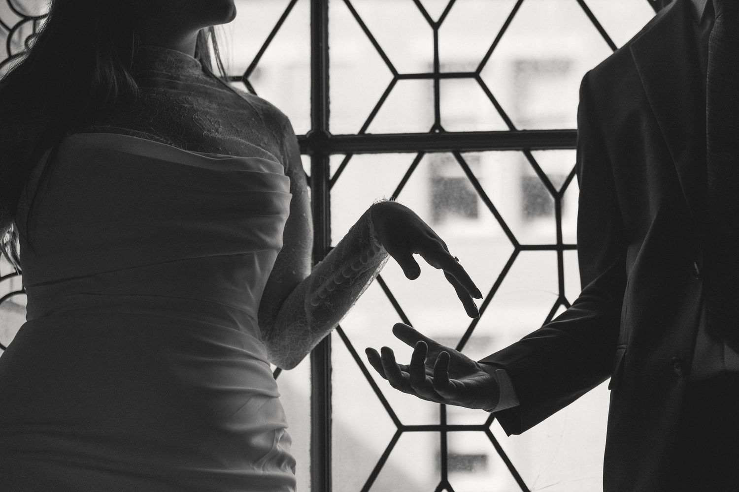 Couple's hands reaching by a window at a San Francisco City Hall elopement, by Sammy Aucella Photography