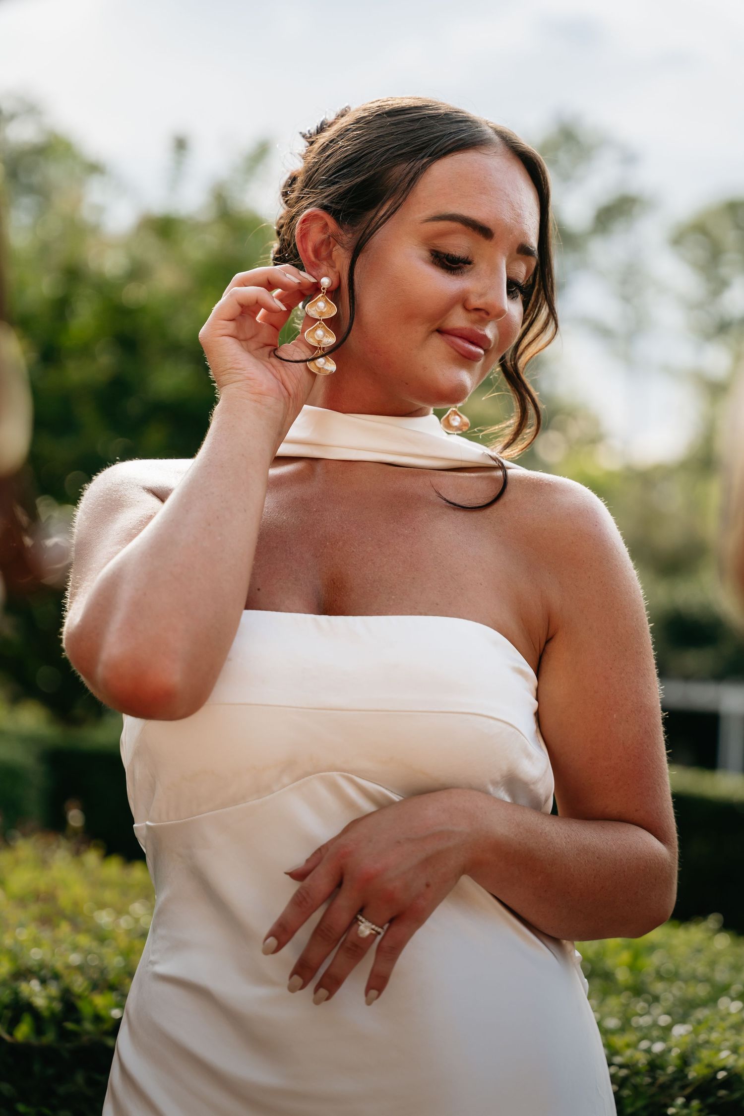 A person in a white off-shoulder dress poses elegantly outdoors in a series of intimate bridal portraits.