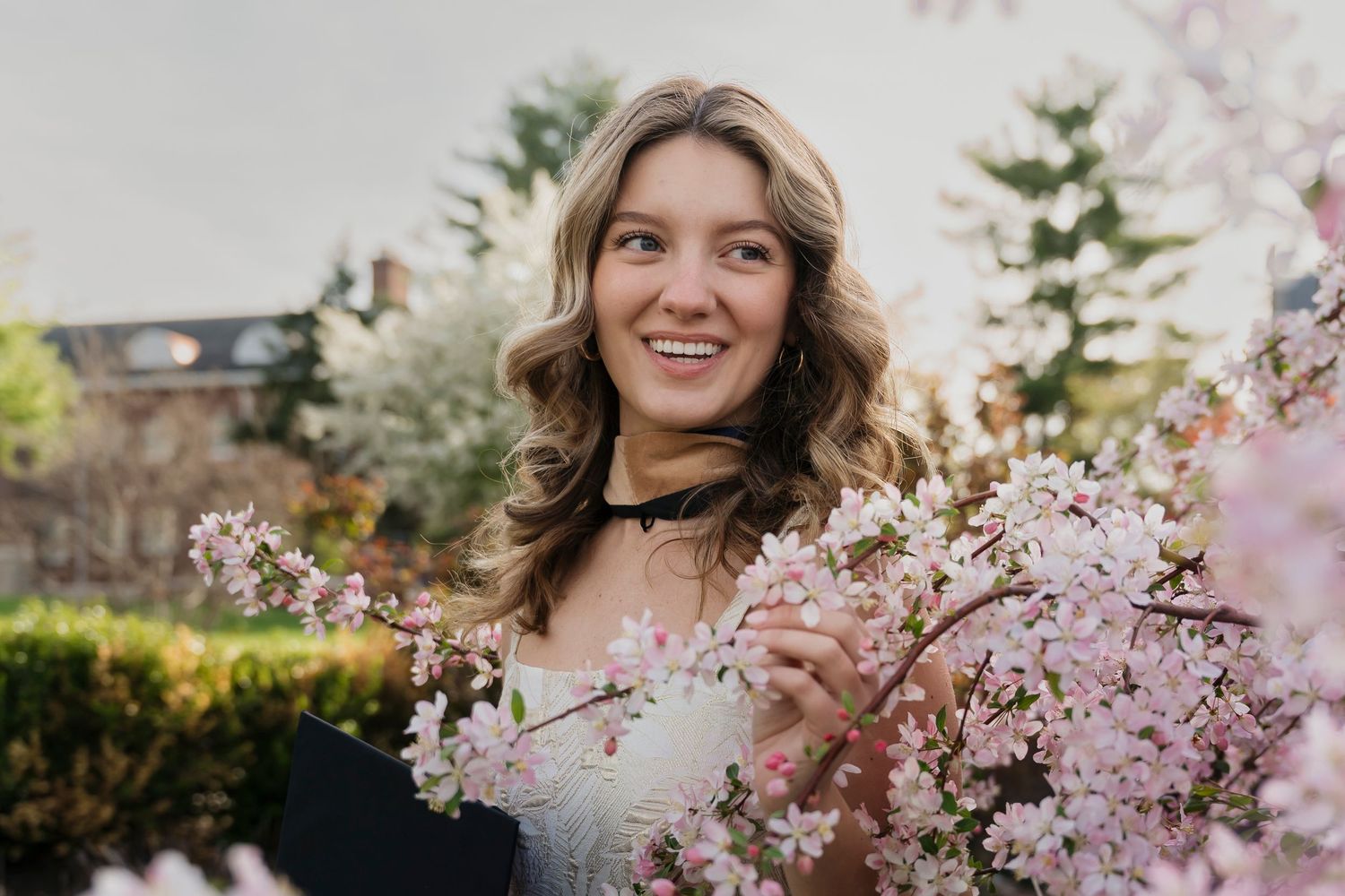 Spring graduation portraits featuring pink cherry blossoms and traditional academic attire.