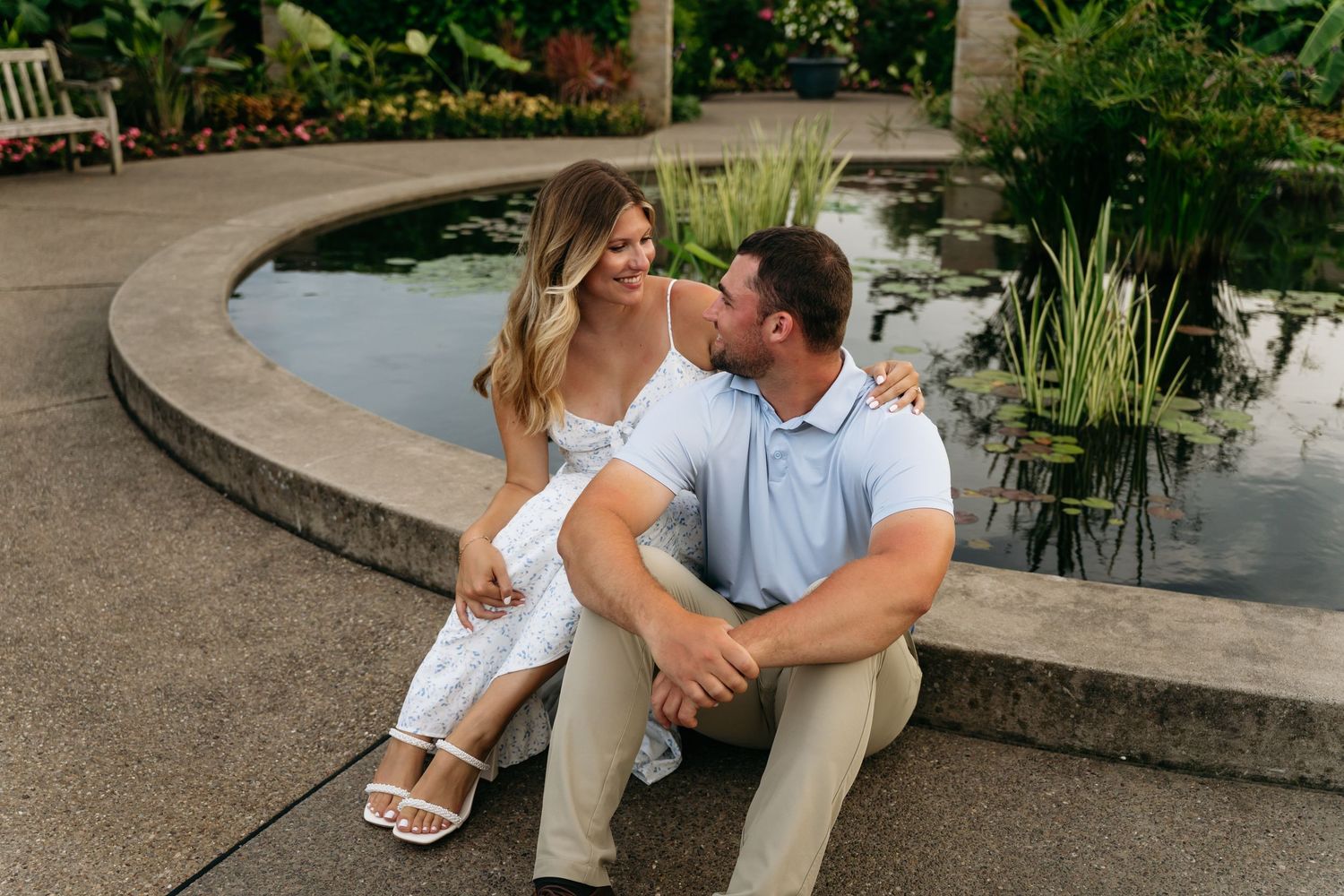 A couple sits together on stone steps in a garden setting during an intimate engagement photo session.