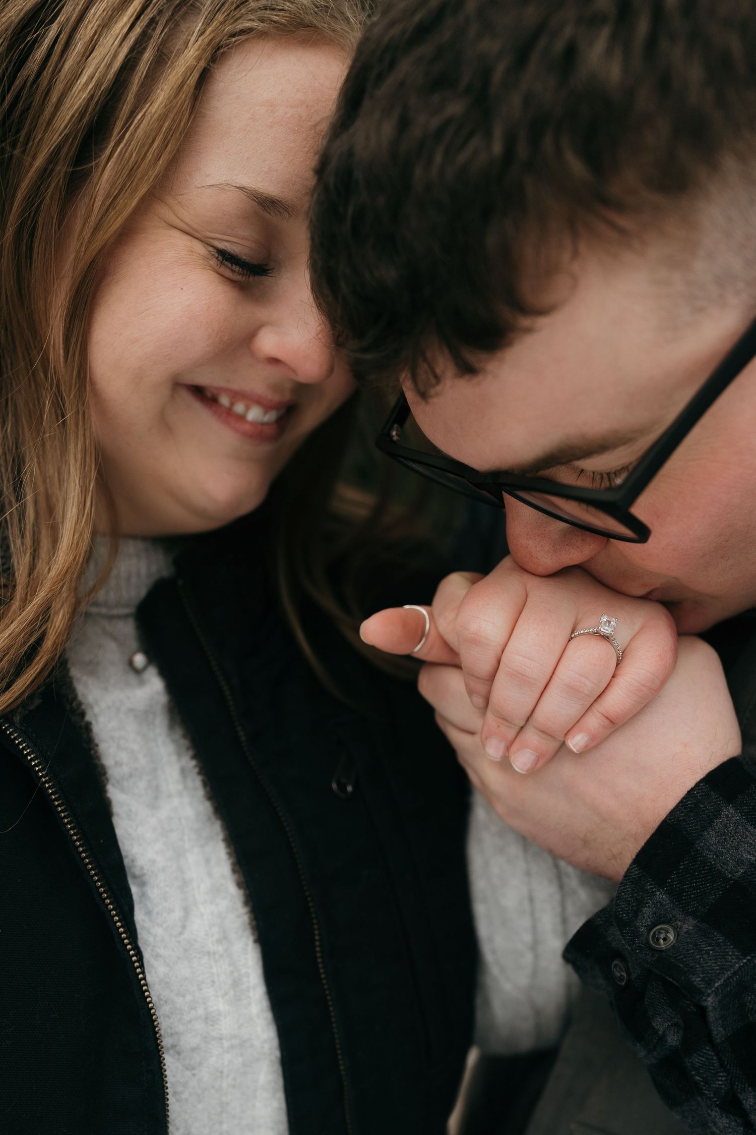 An intimate close-up of a couple sharing a tender moment with an engagement ring.