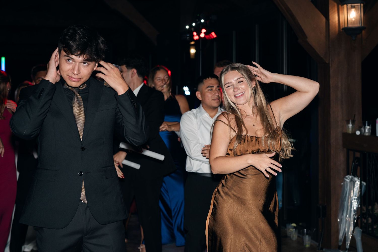 Young couple dancing at a formal event, woman in gold dress and man in black suit, party atmosphere.