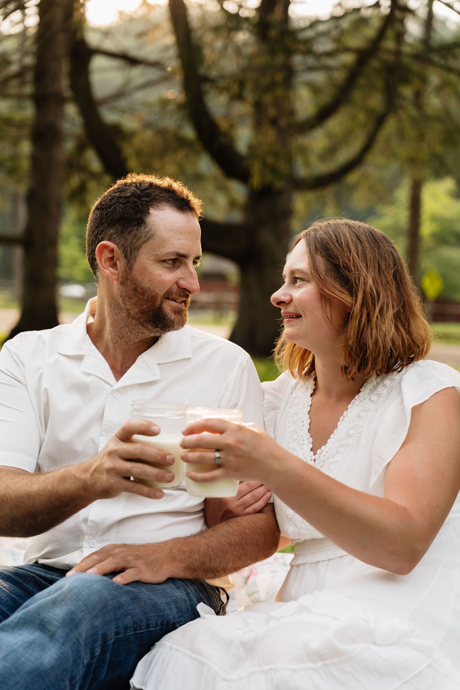 A couple in white shirts sits together outdoors sharing intimate moments in a series of casual romantic photos.