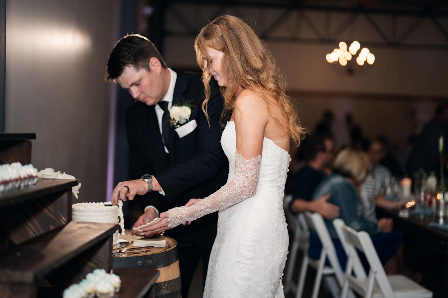 Bride and groom cutting their wedding cake together at a elegant indoor reception venue.