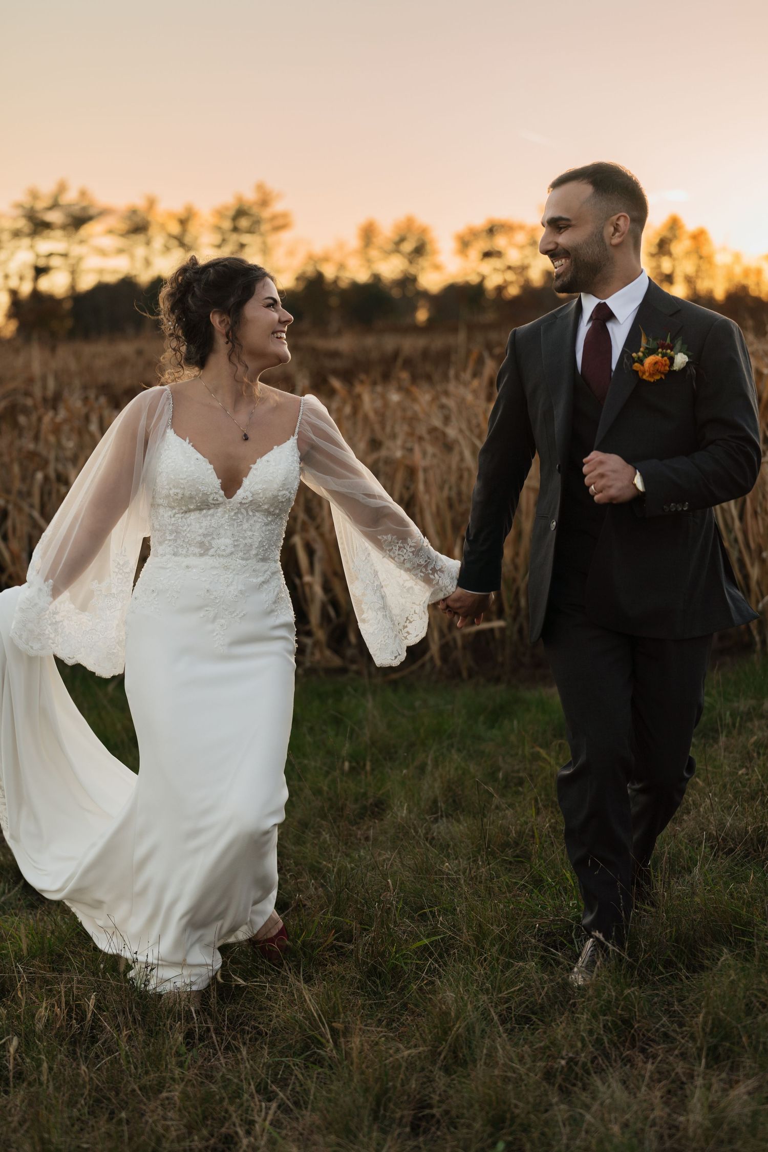 Wedding couple poses in golden hour light against a natural field backdrop.
