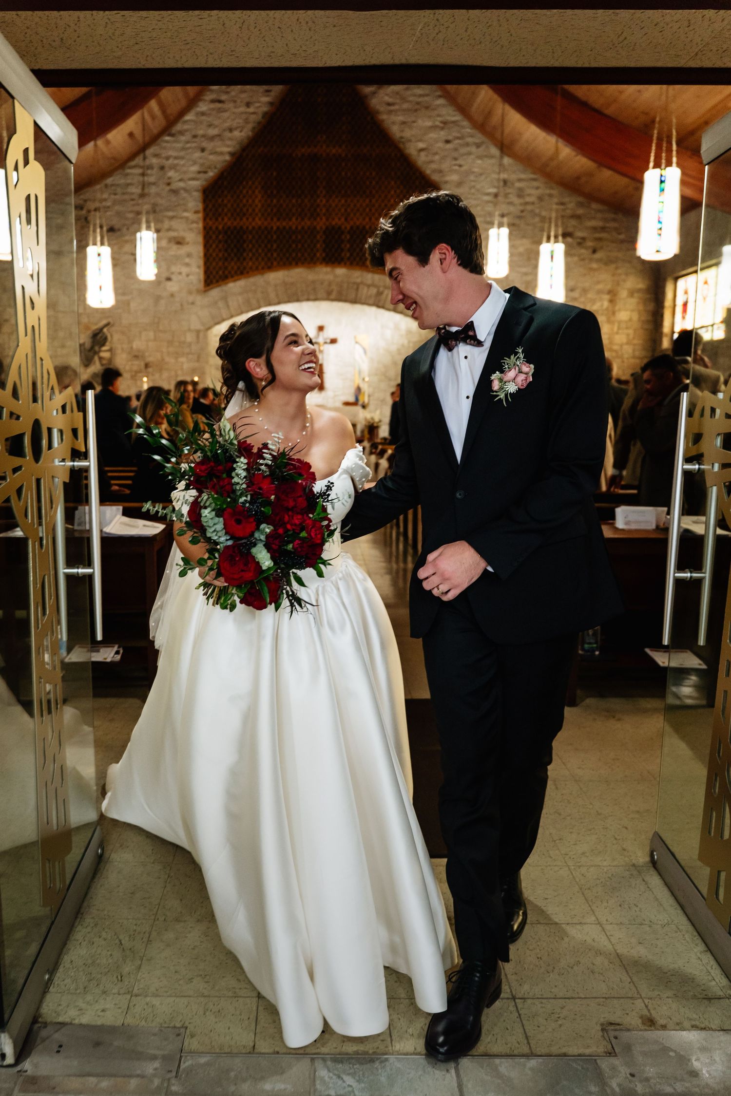 A romantic wedding couple shares a tender dance moment in a rustic venue with hanging pendant lights and brick walls.