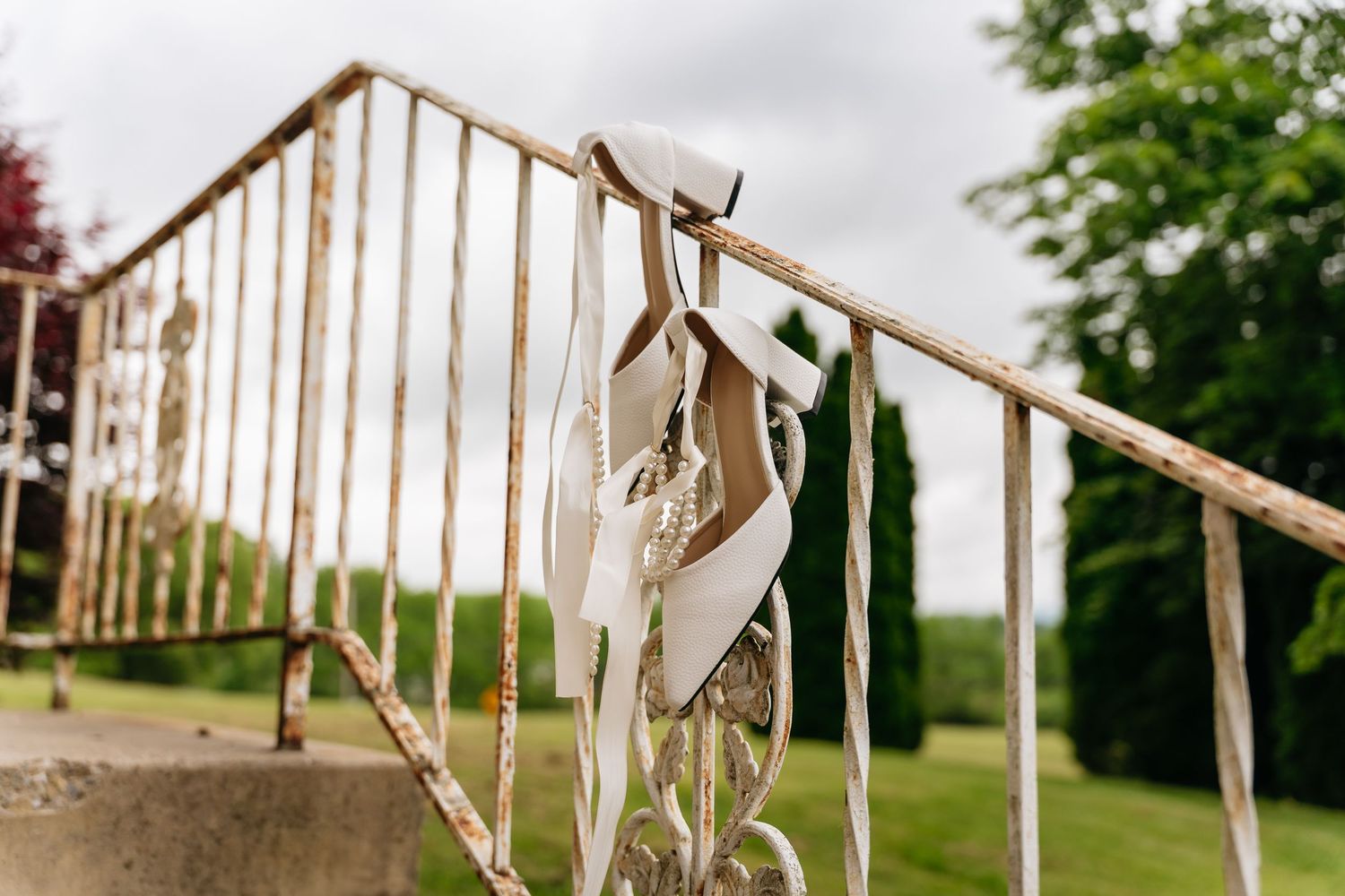 Outdoor wedding ceremony site with white fabric and ribbons decorating wooden poles in a natural setting.