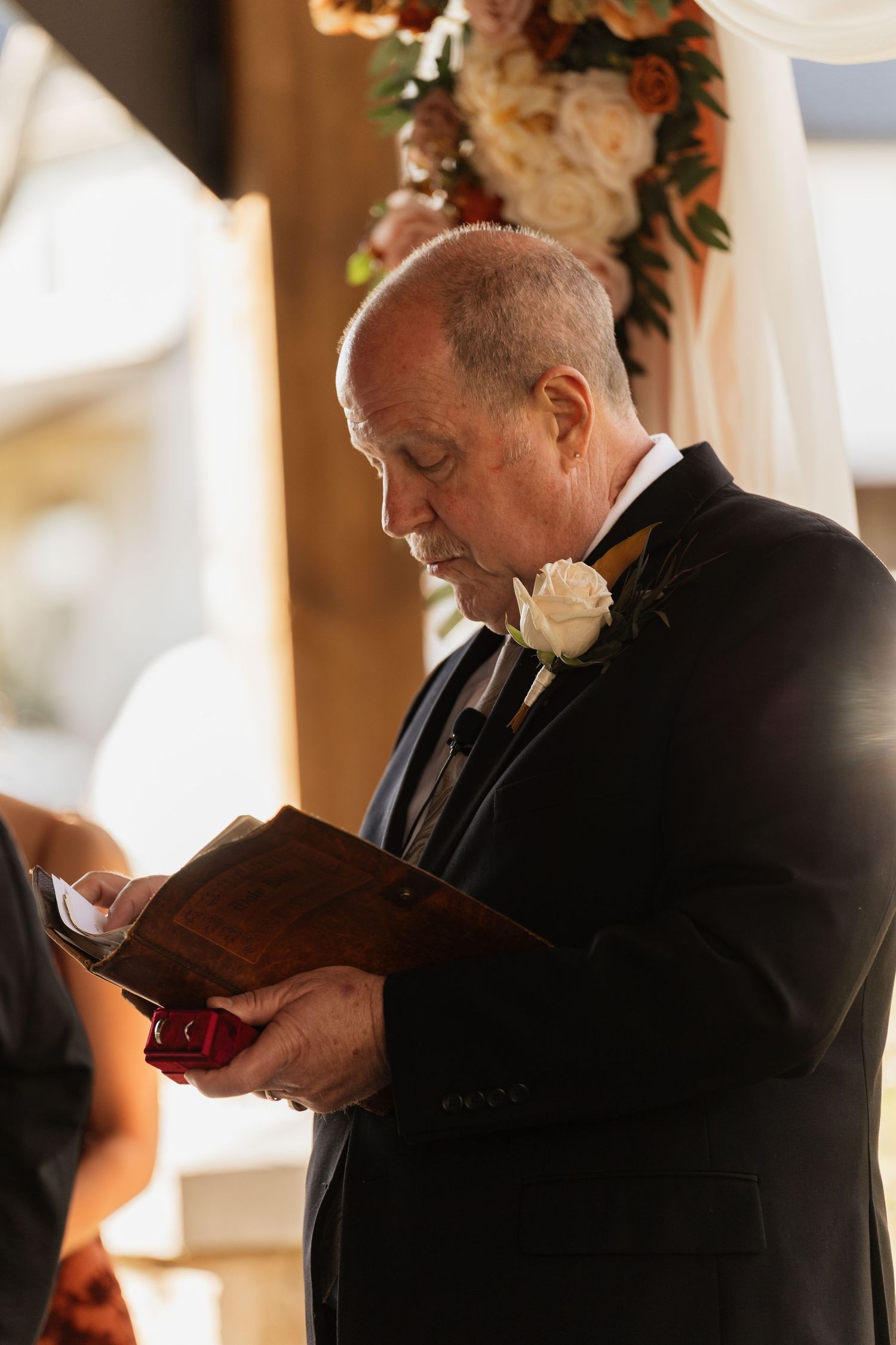 Ceremony readers in formal black attire hold books during intimate indoor wedding service.