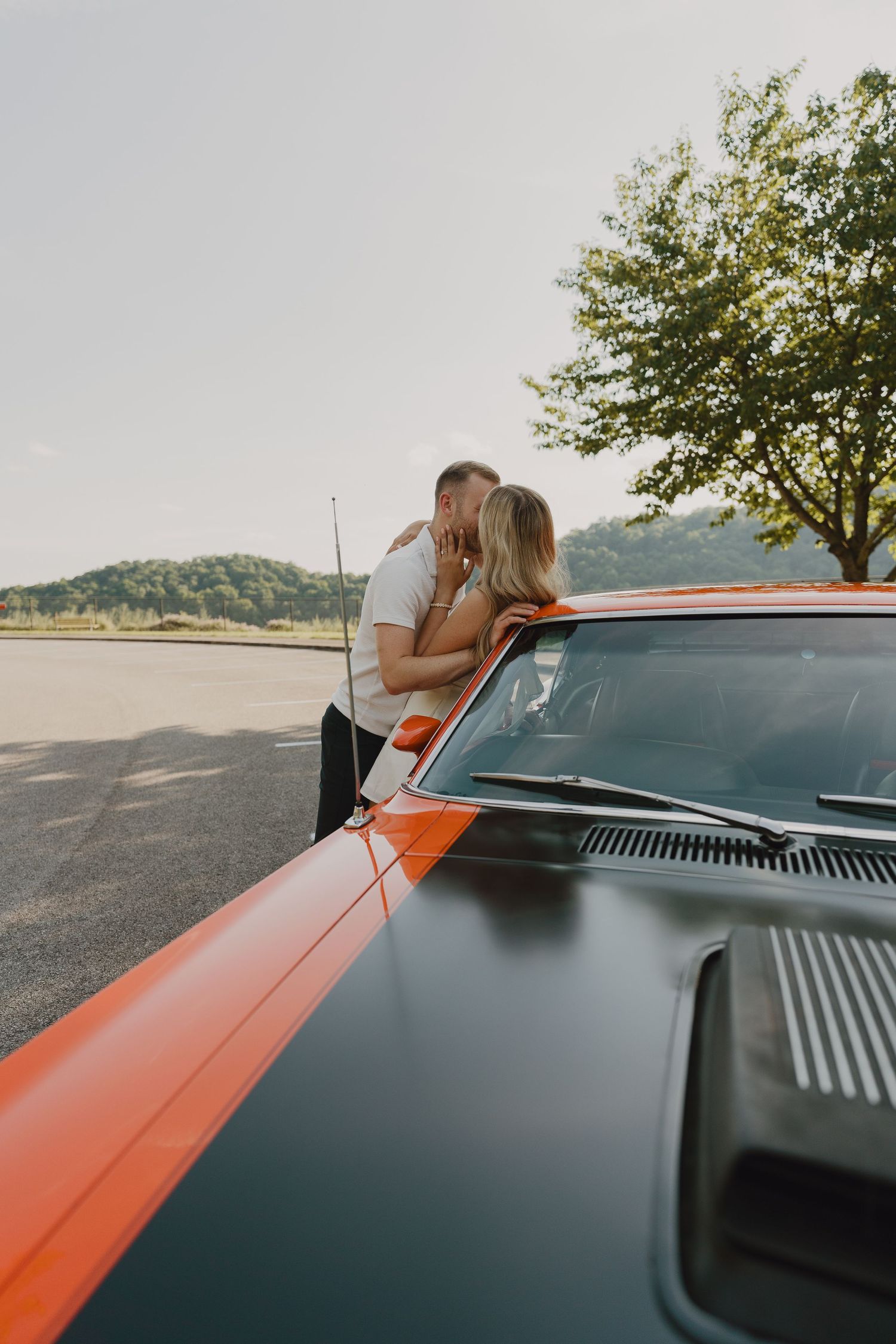 Classic orange and black vintage car photographed from the hood on a scenic overlook.