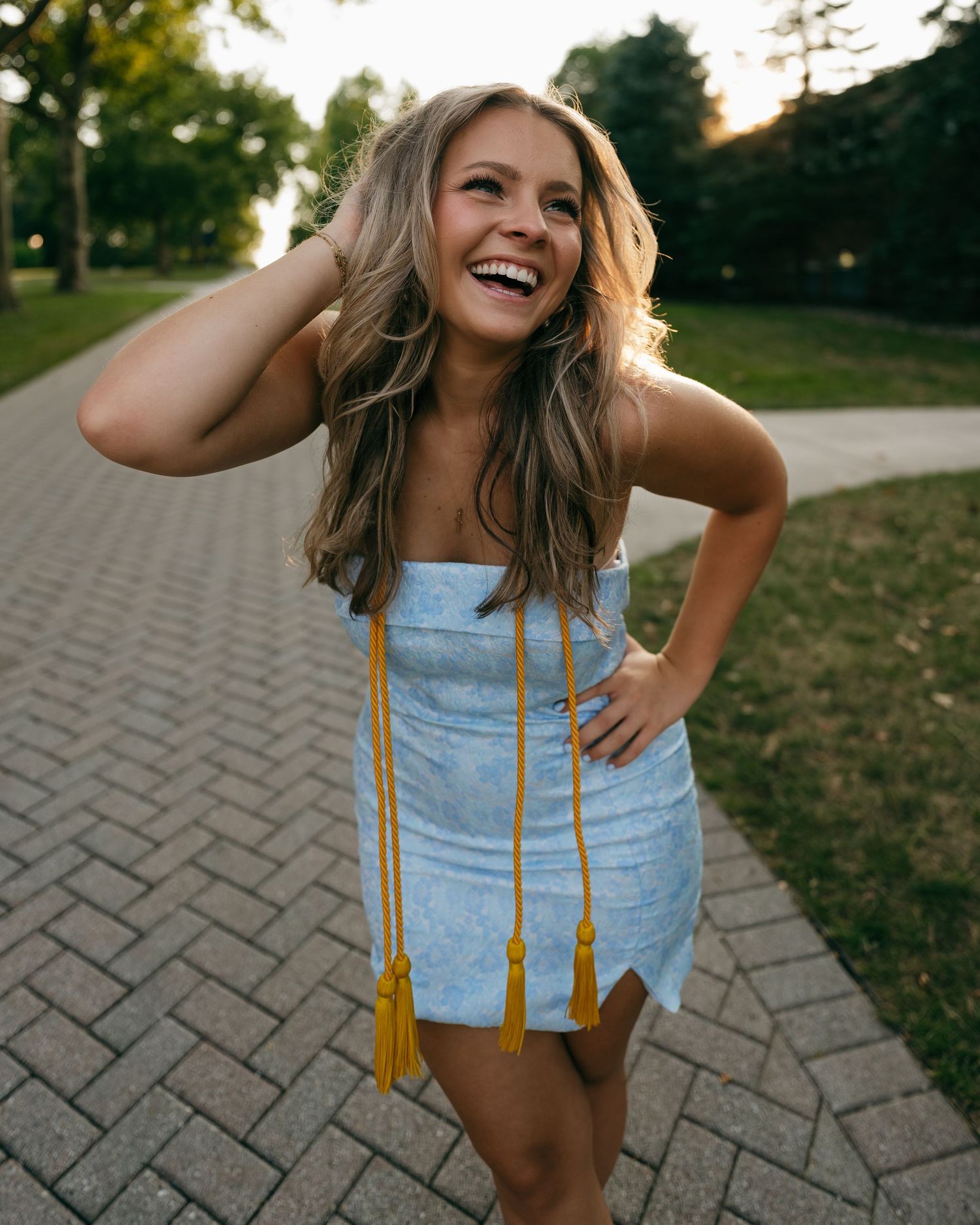 A joyous candid portrait on a brick pathway with trees and greenery in the background.
