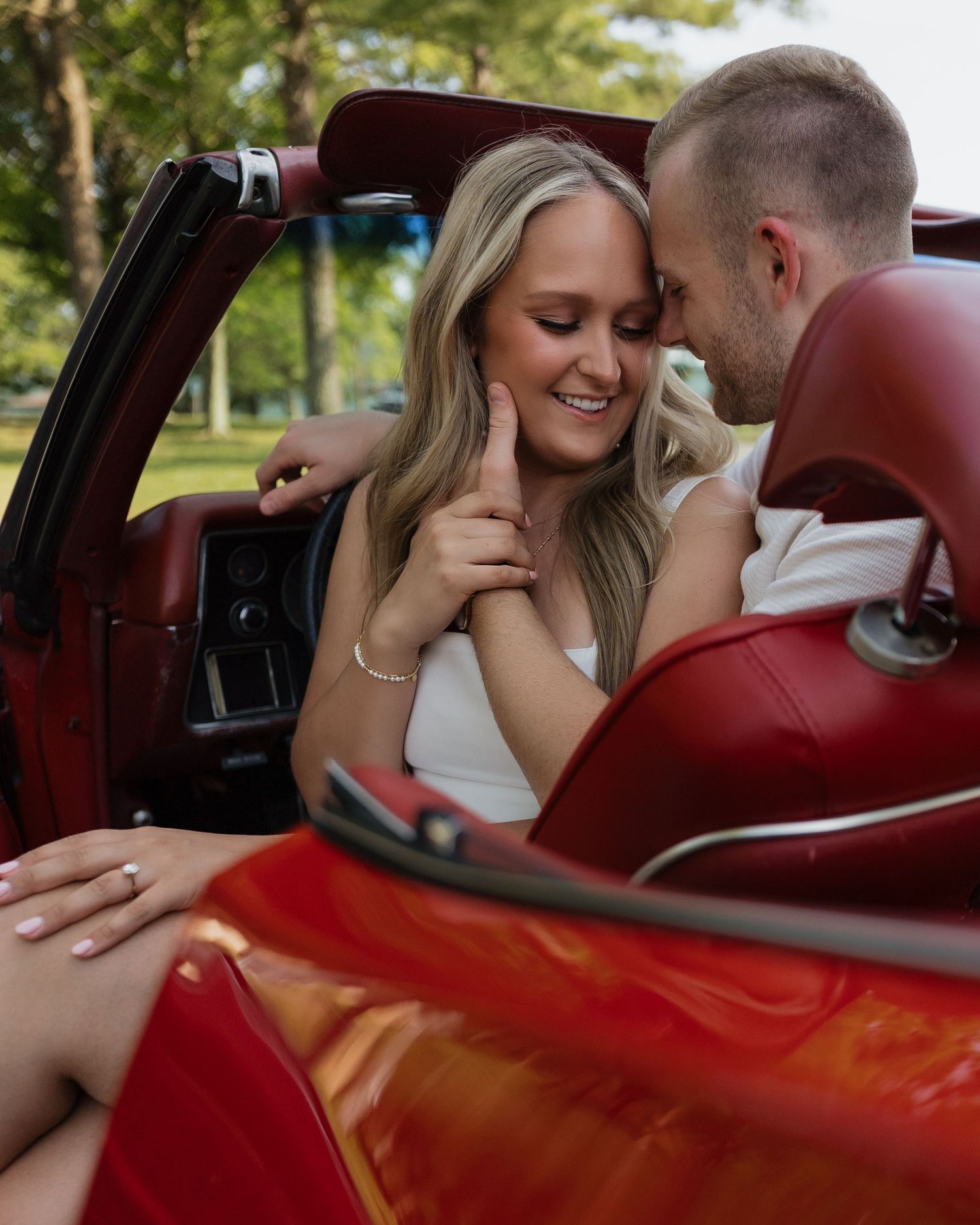 Intimate moments captured inside a classic car with red leather seats.