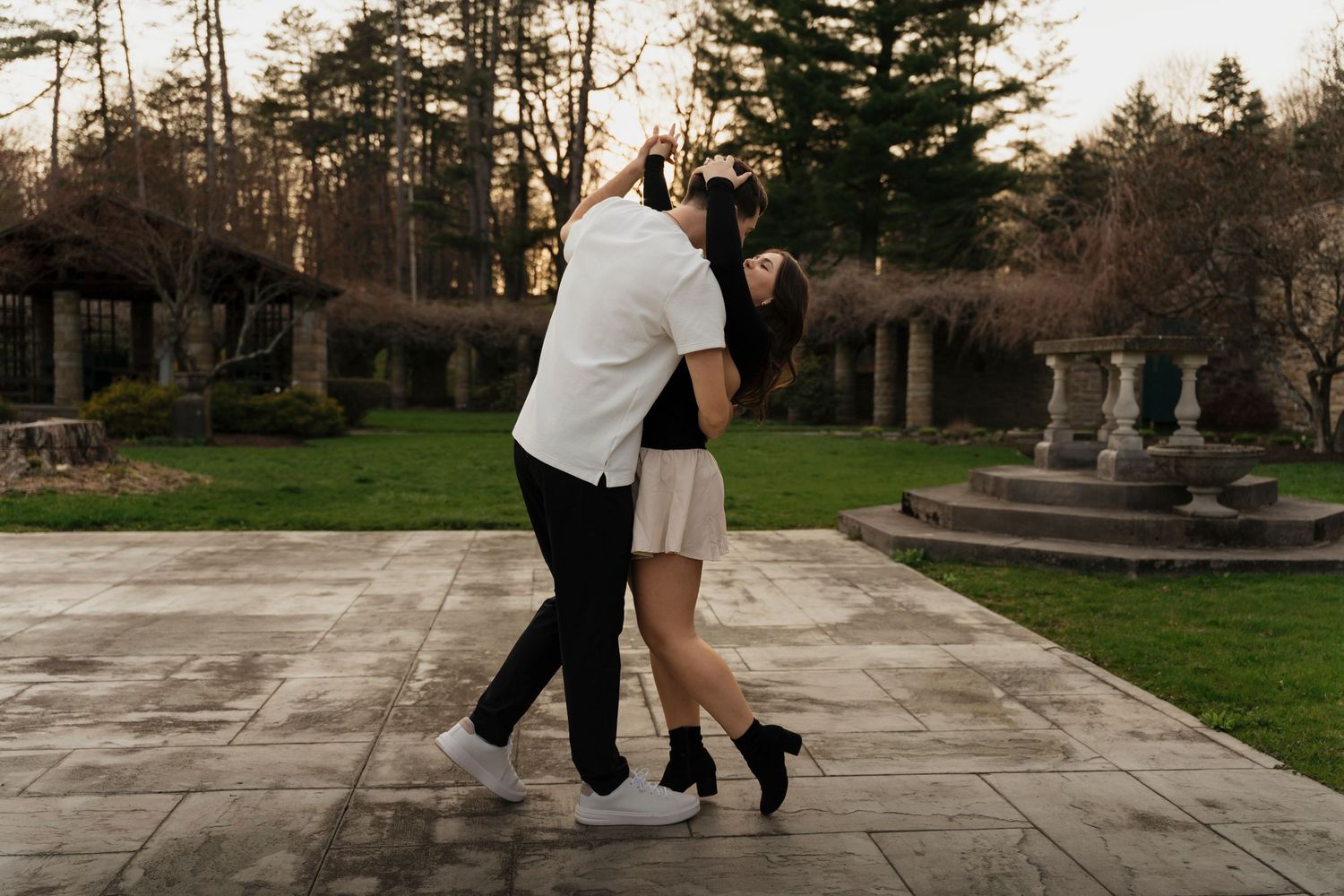Joyful engaged couple dancing through sunlit gardens at Mount Assisi during Pennsylvania engagement session