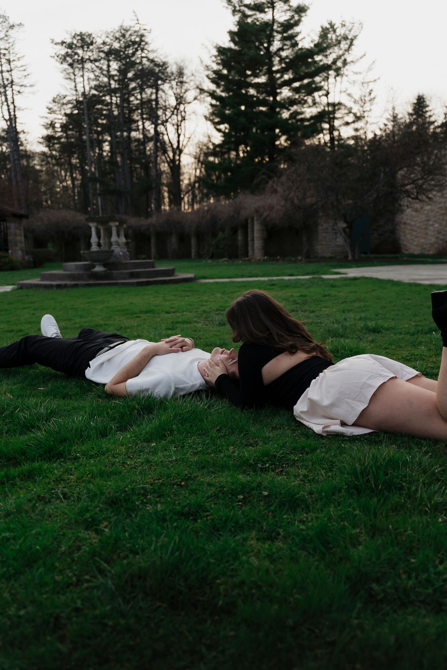 Joyful engaged couple rolling through sunlit gardens at Mount Assisi during Pennsylvania engagement session