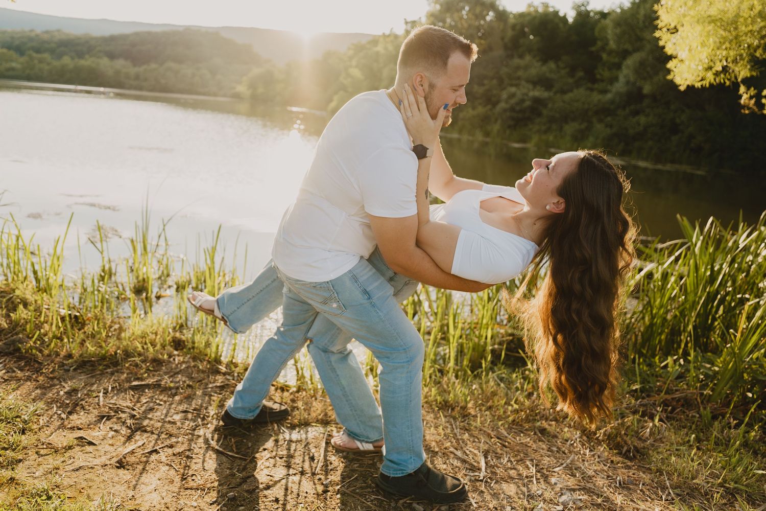 A romantic couple dips while dancing by the lakeside during golden hour.