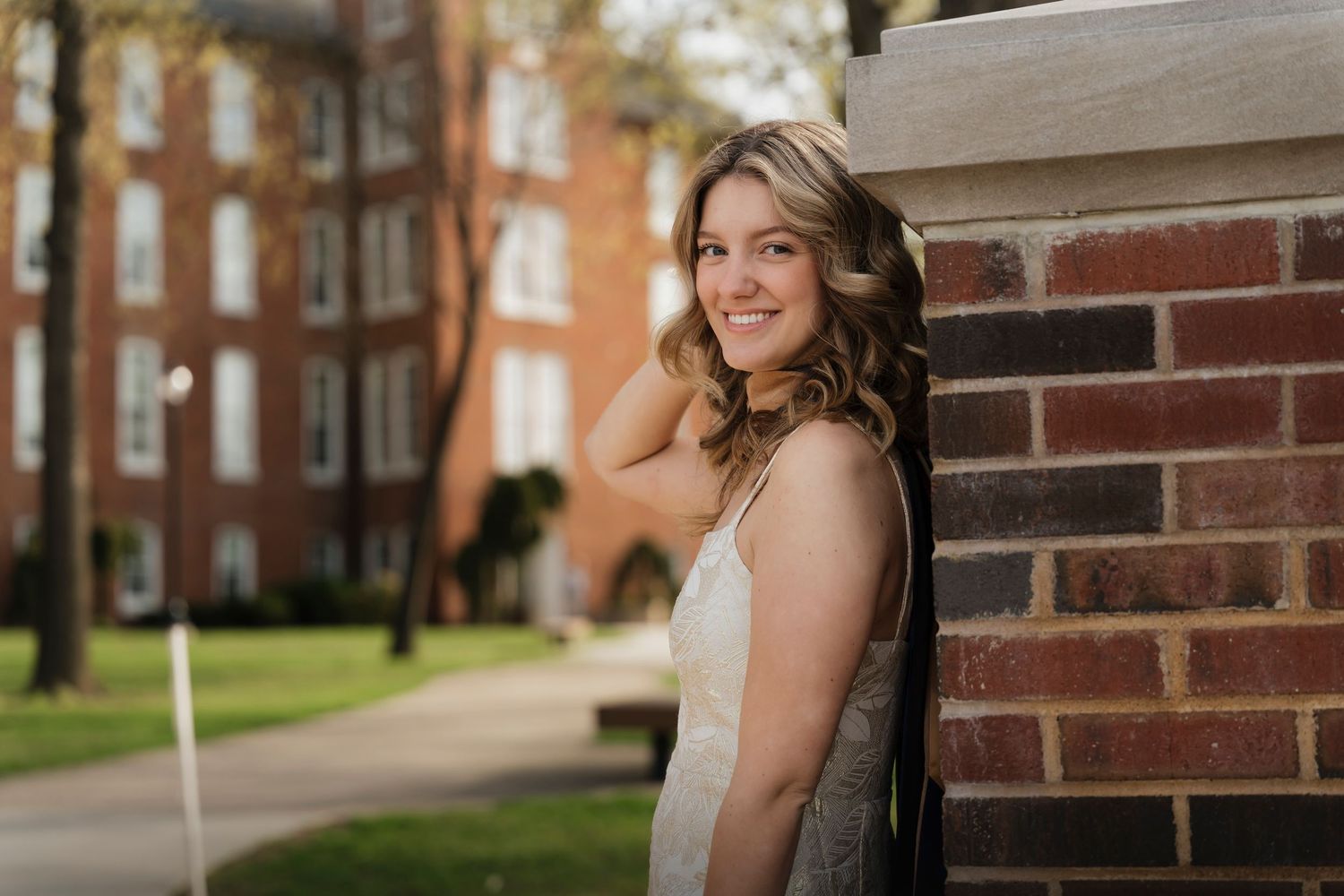 Spring graduation photos captured by a brick building with blooming cherry trees in the background.