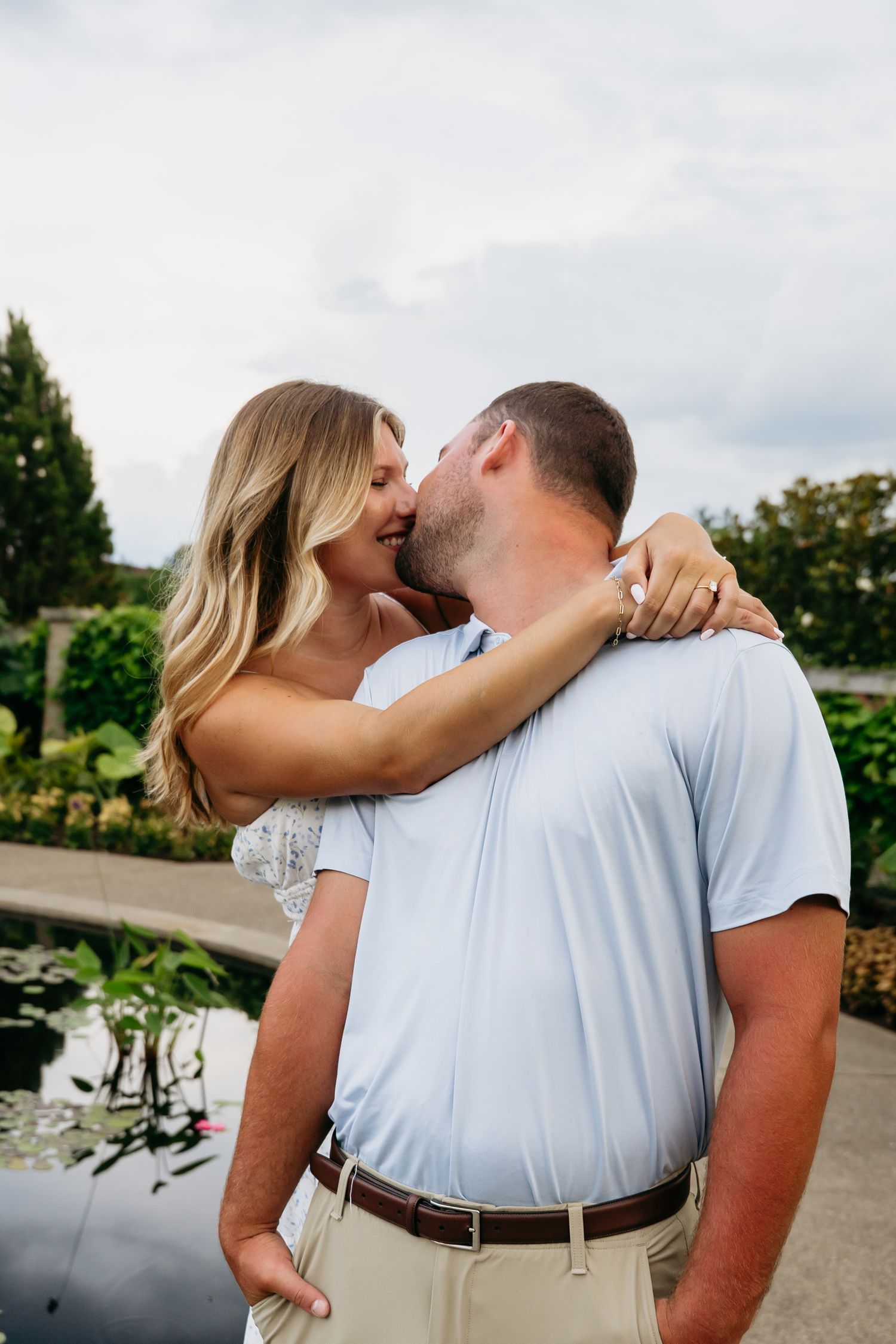 A couple in matching white outfits share an intimate moment outdoors in a romantic photo series.