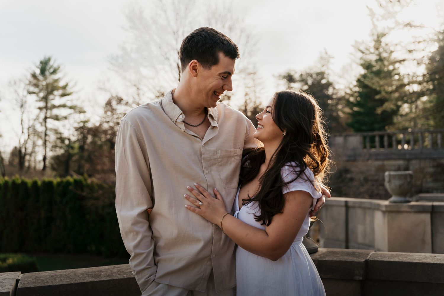 Elegant engagement portrait of couple in white outfits against 106-year-old estate garden in Loretto PA