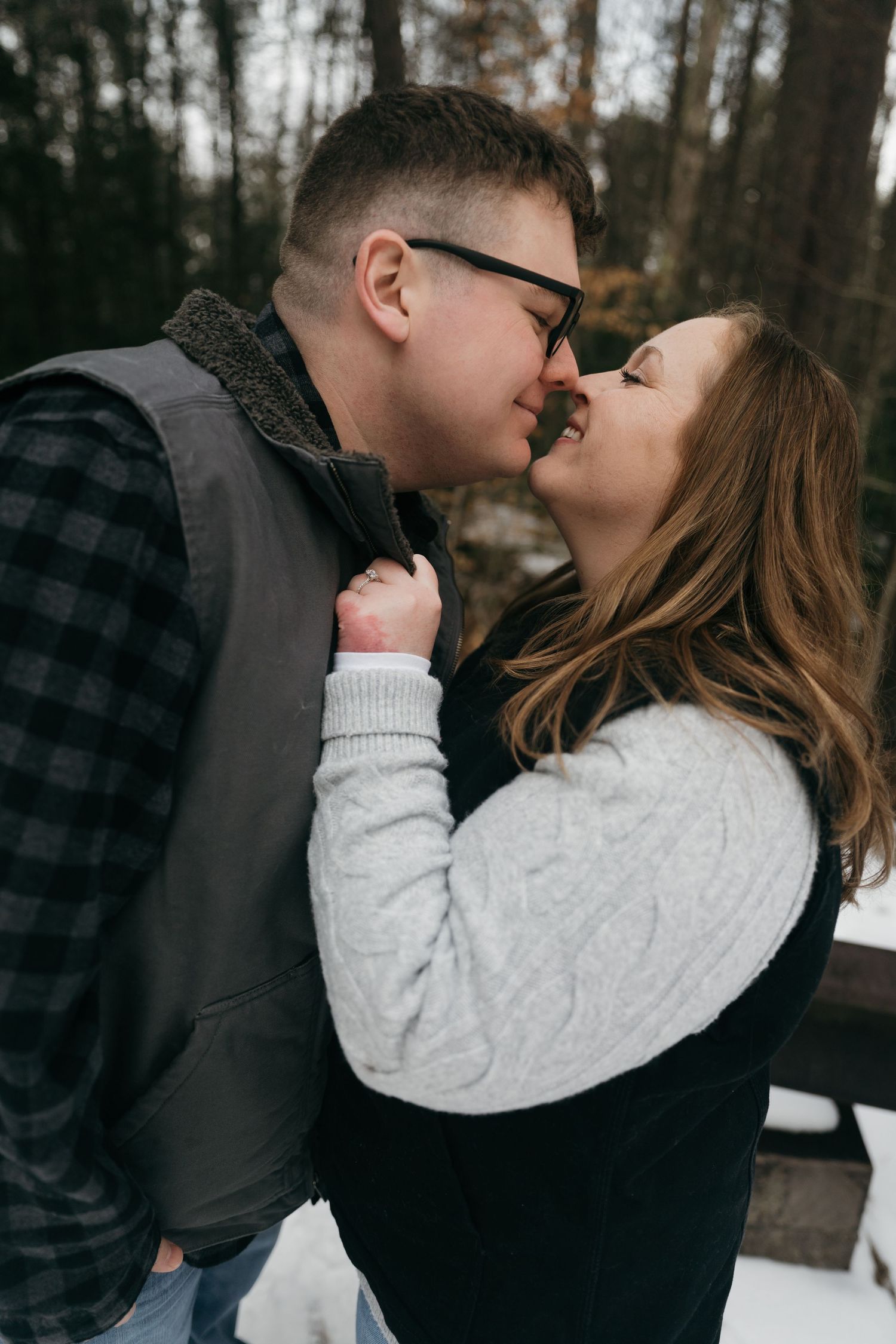 A romantic winter photoshoot features a couple in cozy sweaters sharing a close moment.