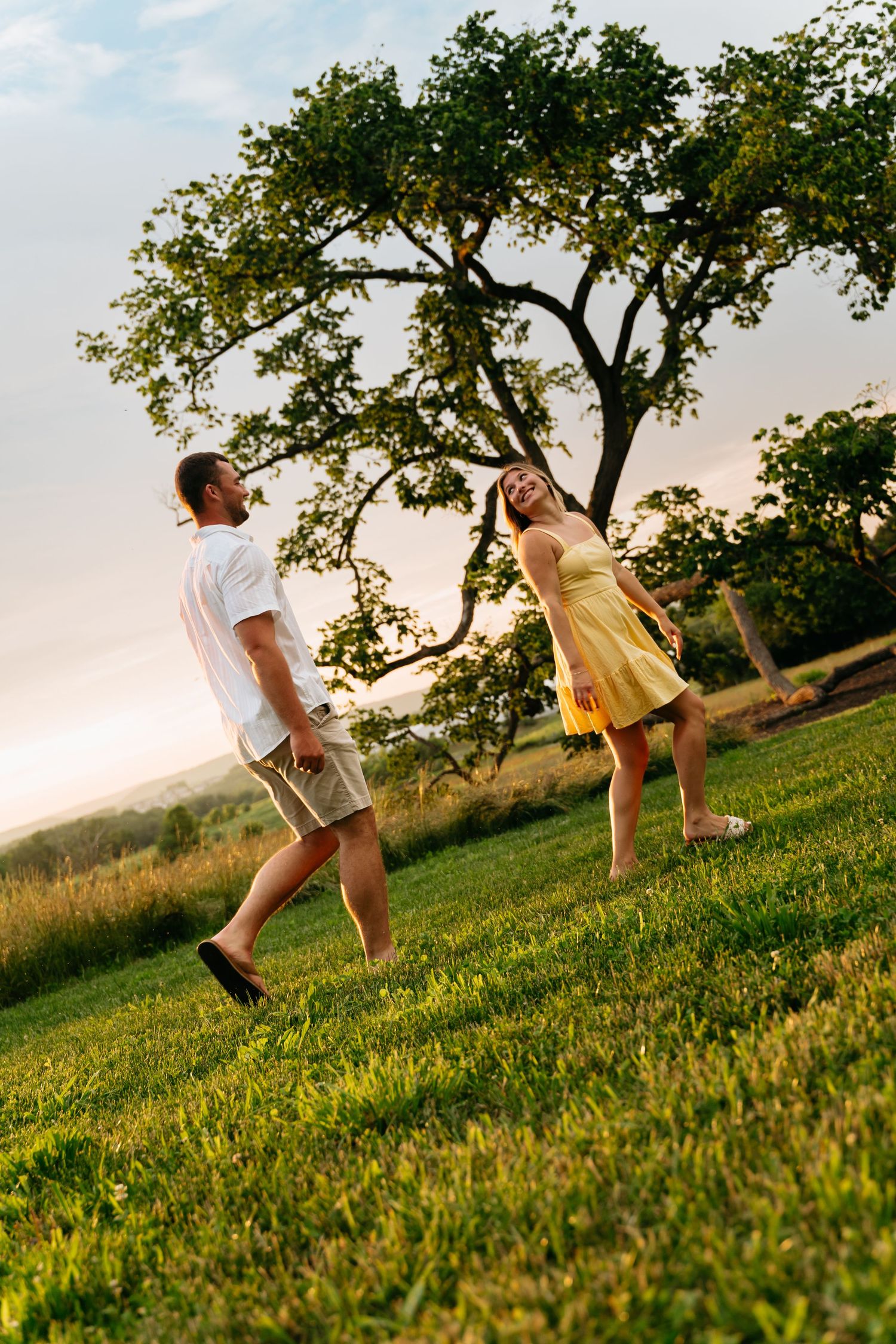 People playing on a grassy hillside at sunset, creating a playful silhouette against the golden evening light.