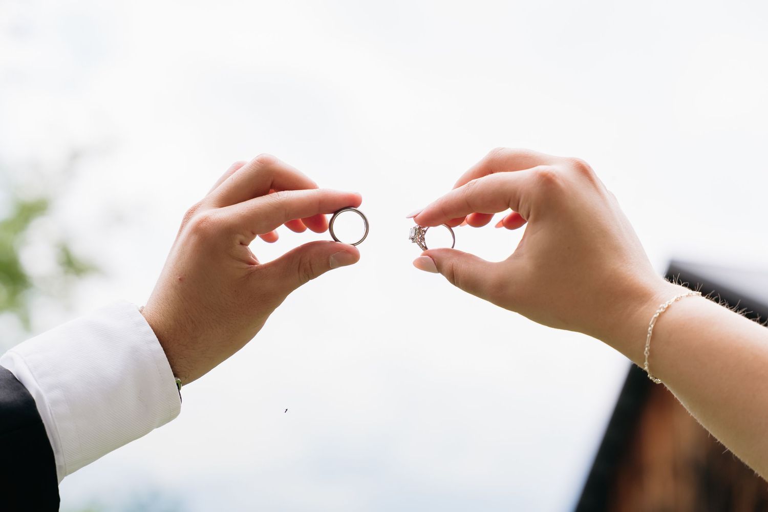 Close up of wedding rings being exchanged during a ceremony with hands in focus against blurred background.