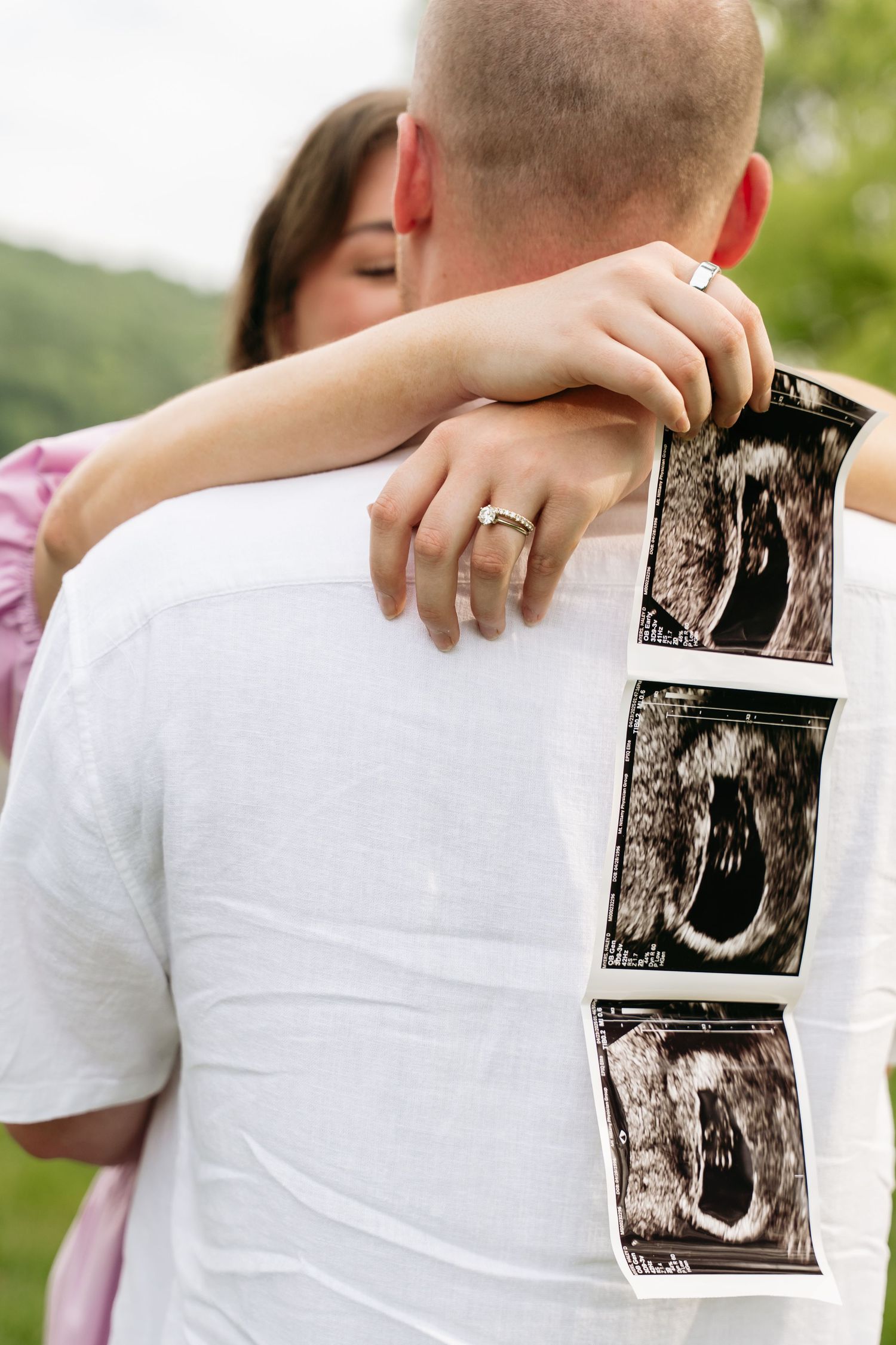 Close up of couple holding ultrasound photos during outdoor pregnancy announcement photoshoot.
